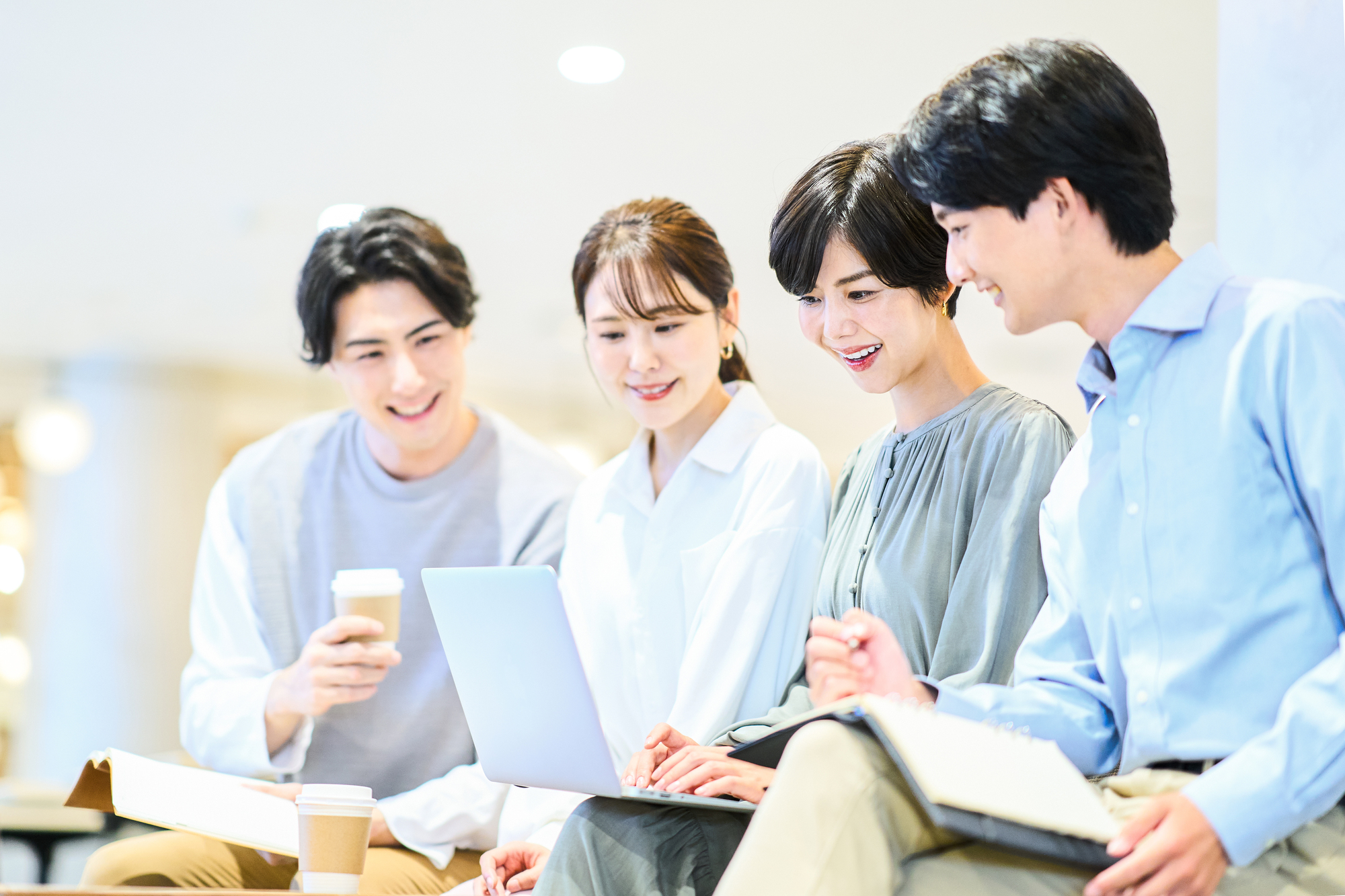 パソコンの画面を笑顔で眺める4人の男女