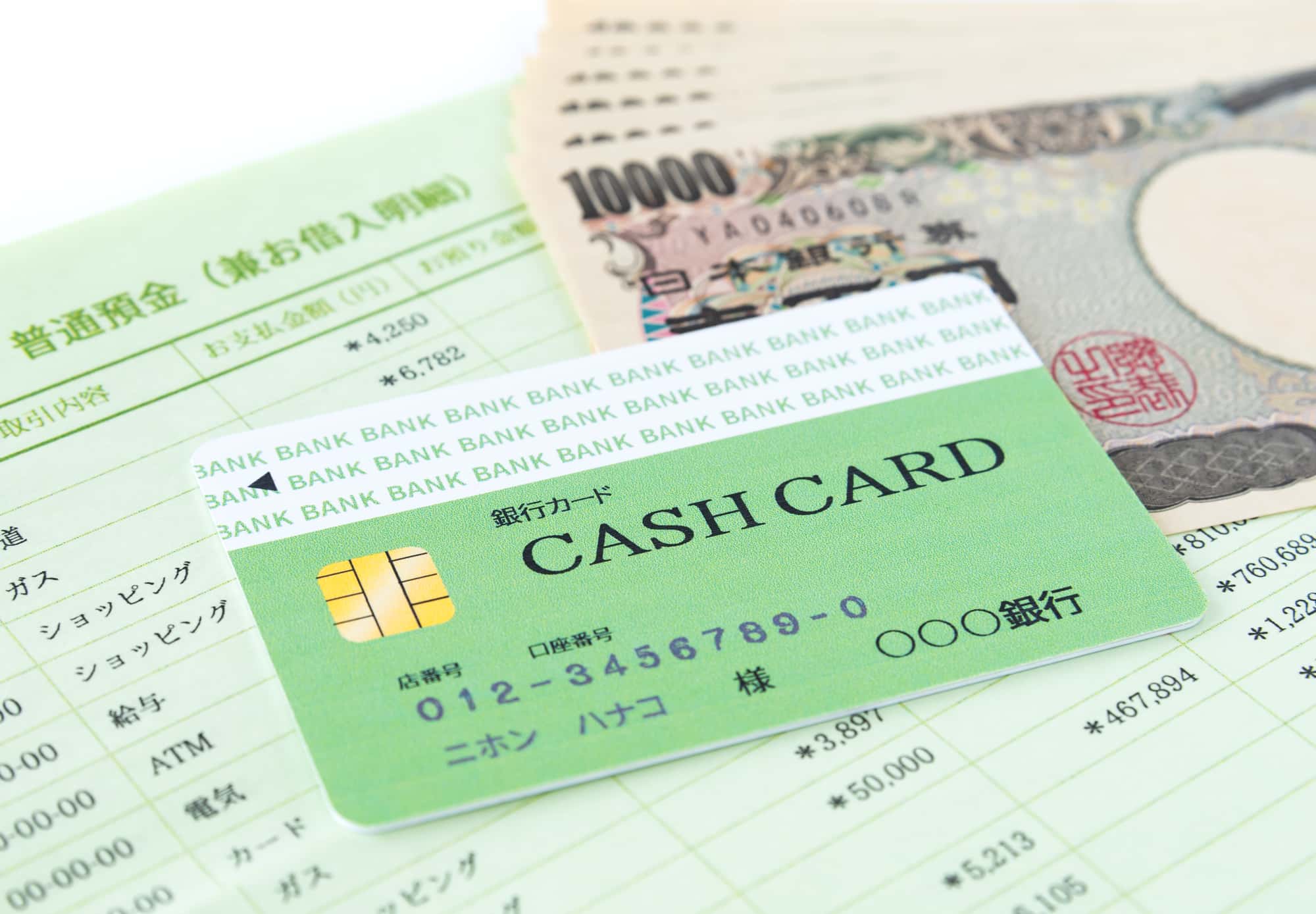 通帳の上に置かれたキャッシュカードと数枚の一万円札