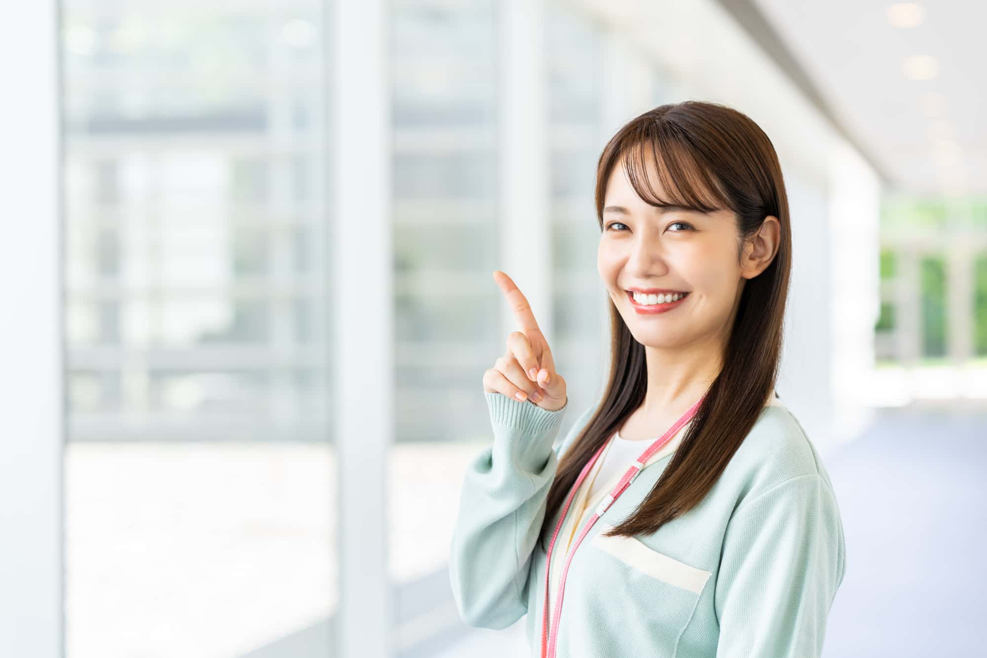 オフィスで上を指さす笑顔の女性