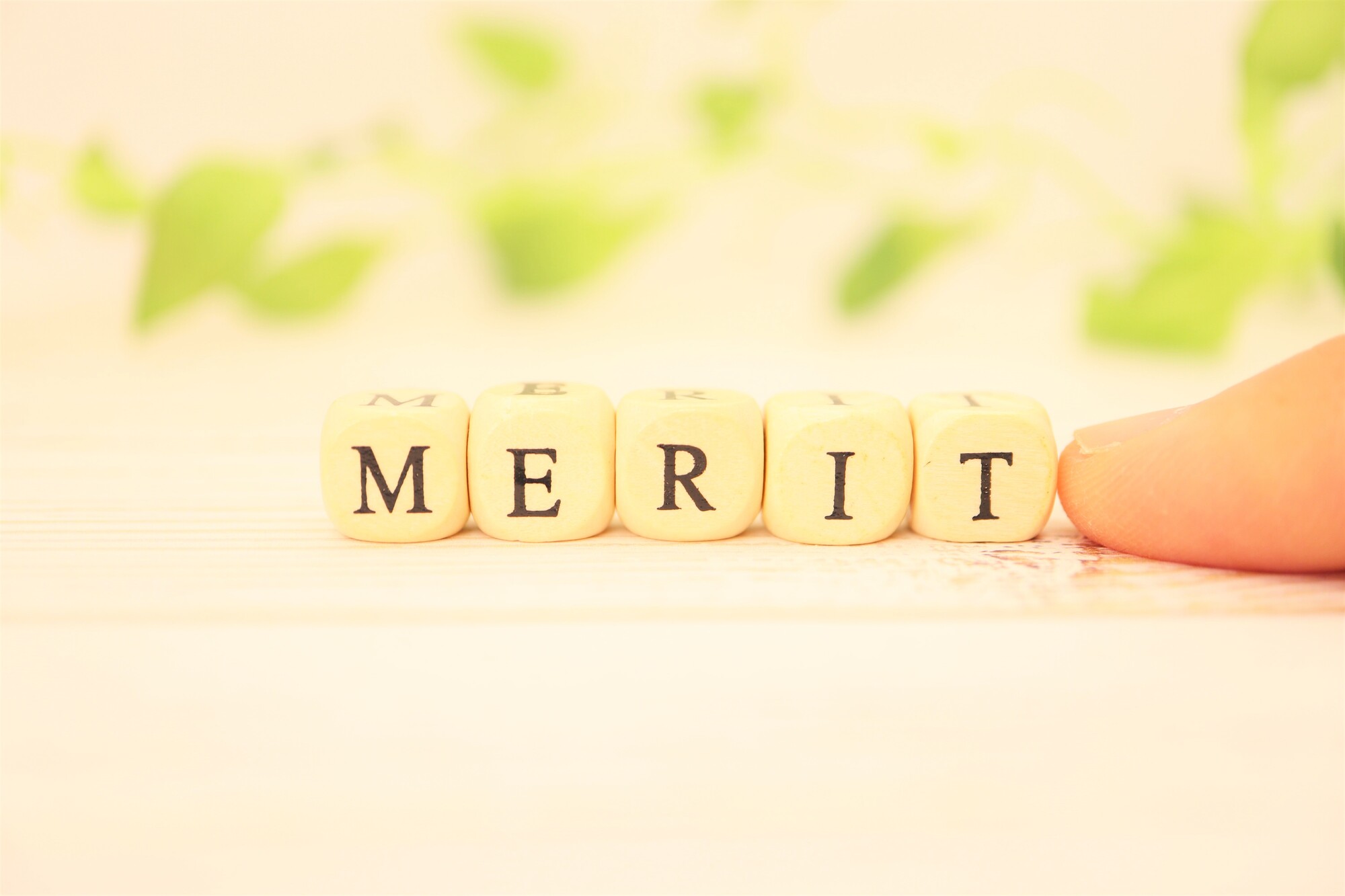 「MERIT」と書かれた小さなブロックと指先