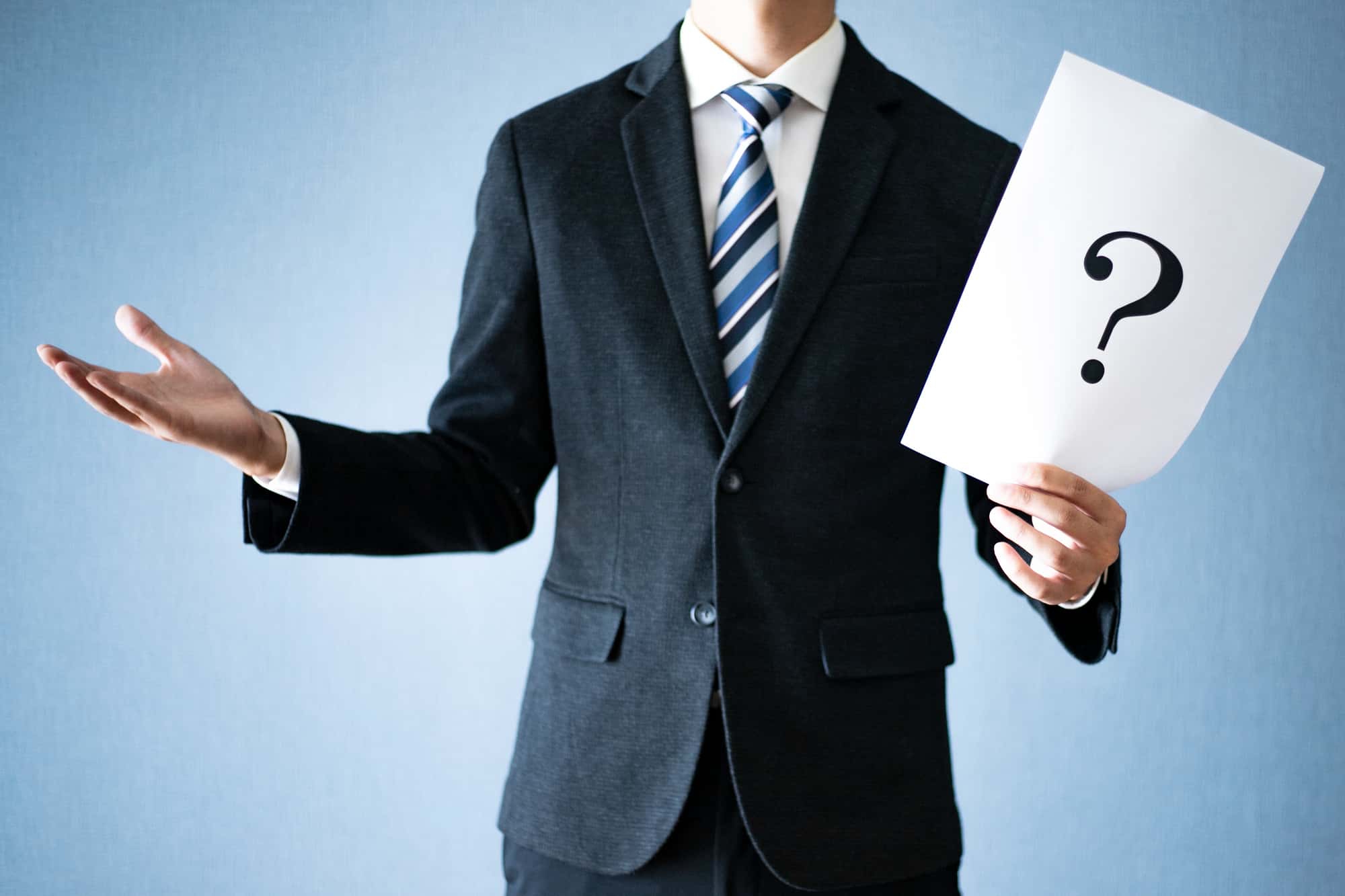 クエスチョンマークが書かれた紙を持つビジネスパーソン