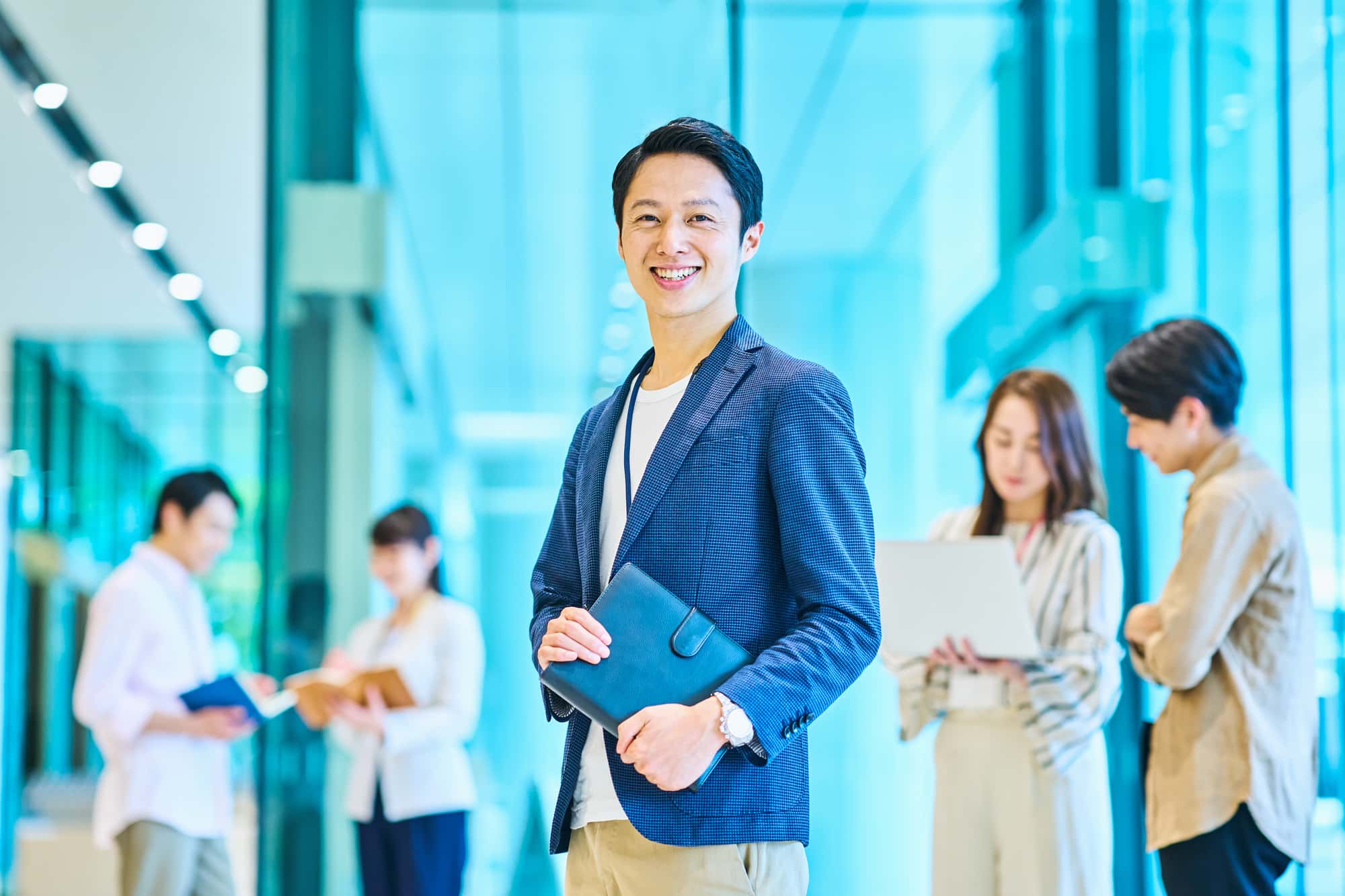 オフィスで笑顔を浮かべるビジネスパーソンと4人の同僚