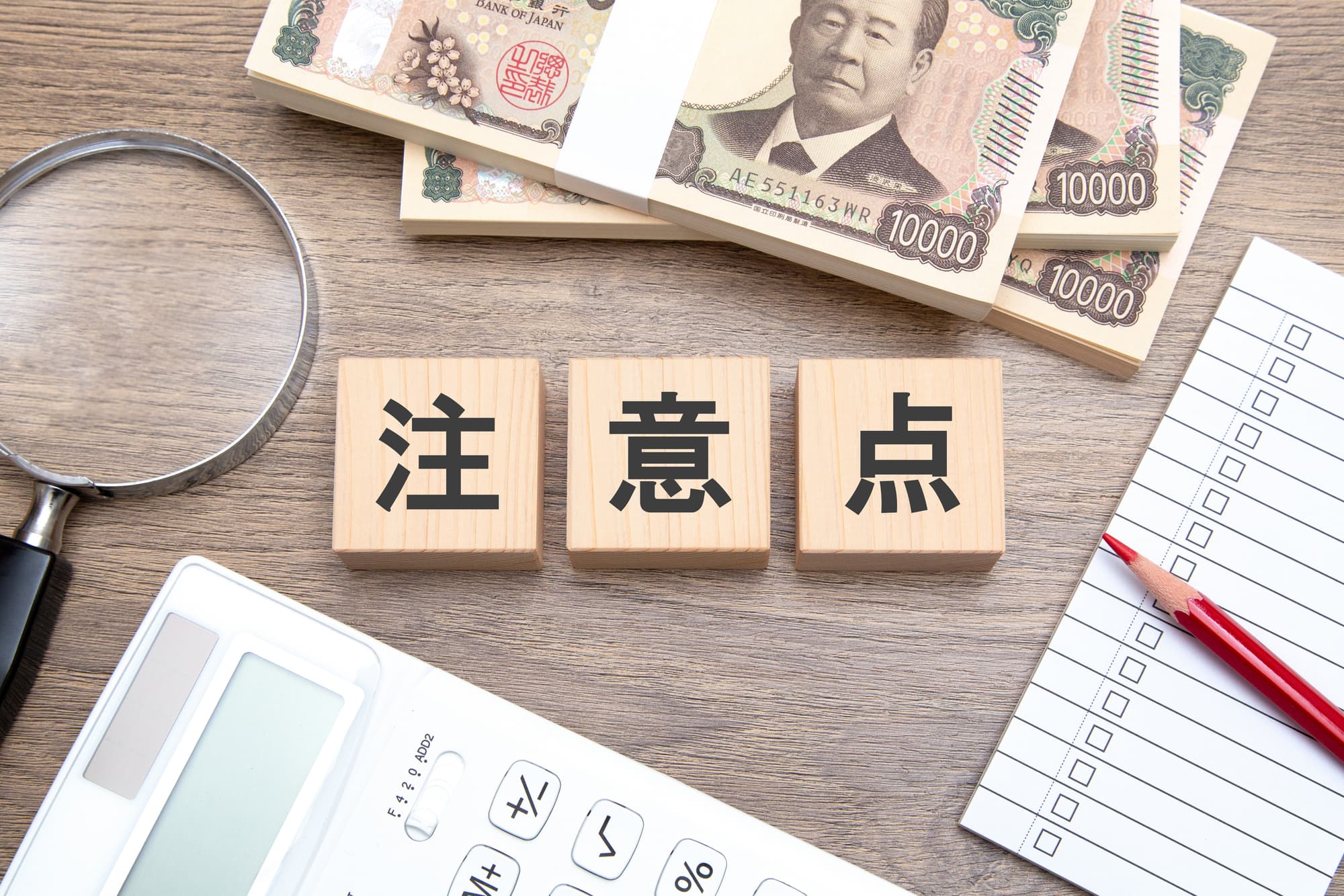 注意点と書かれたブロックとルーペ・電卓・メモ帳・紙幣