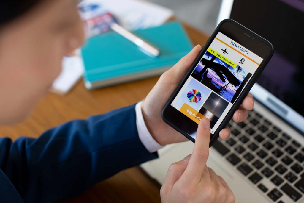 PCの前でスマホを操作している人