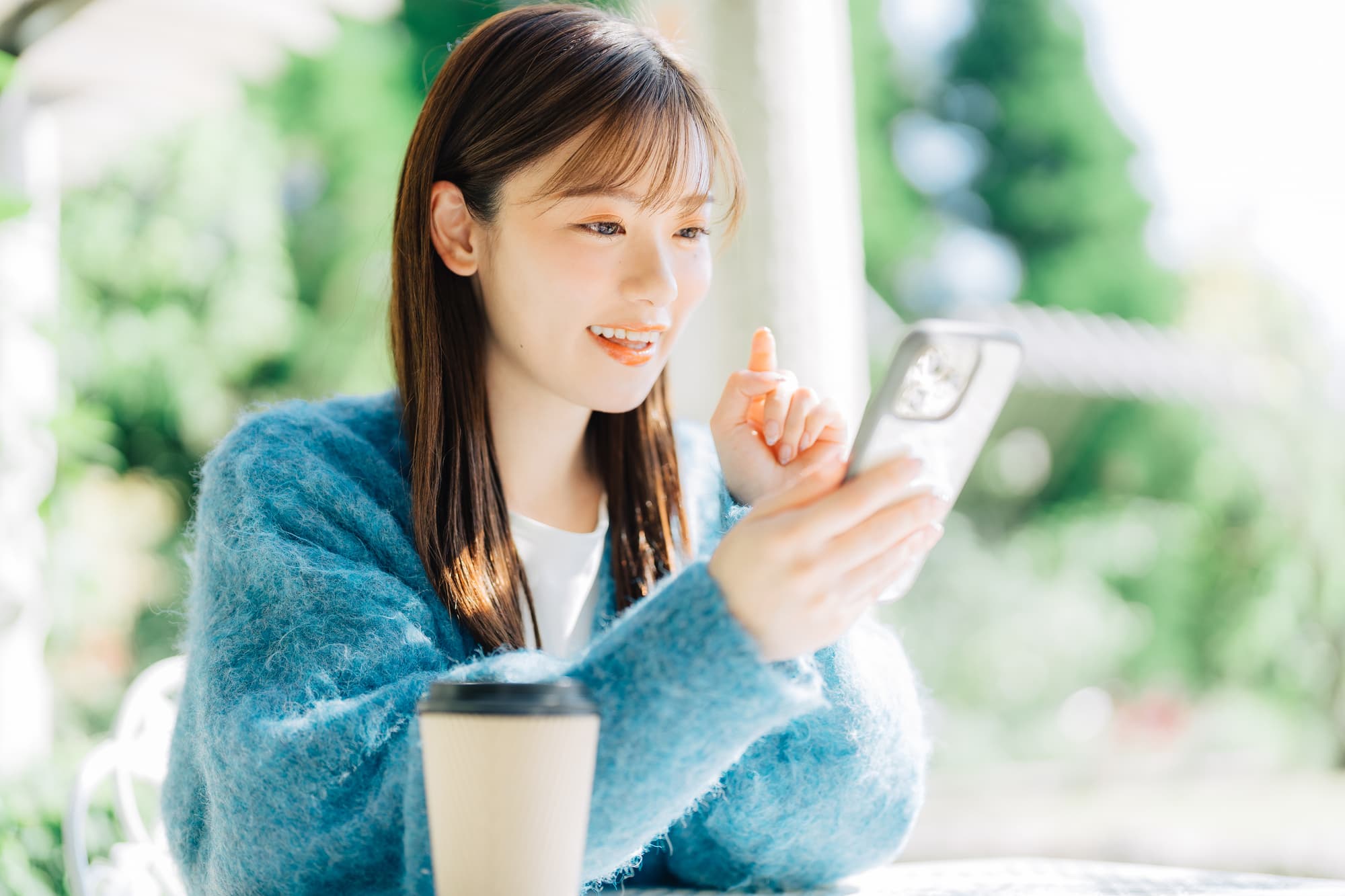 スマートフォンを操作しながら笑顔を浮かべる女性