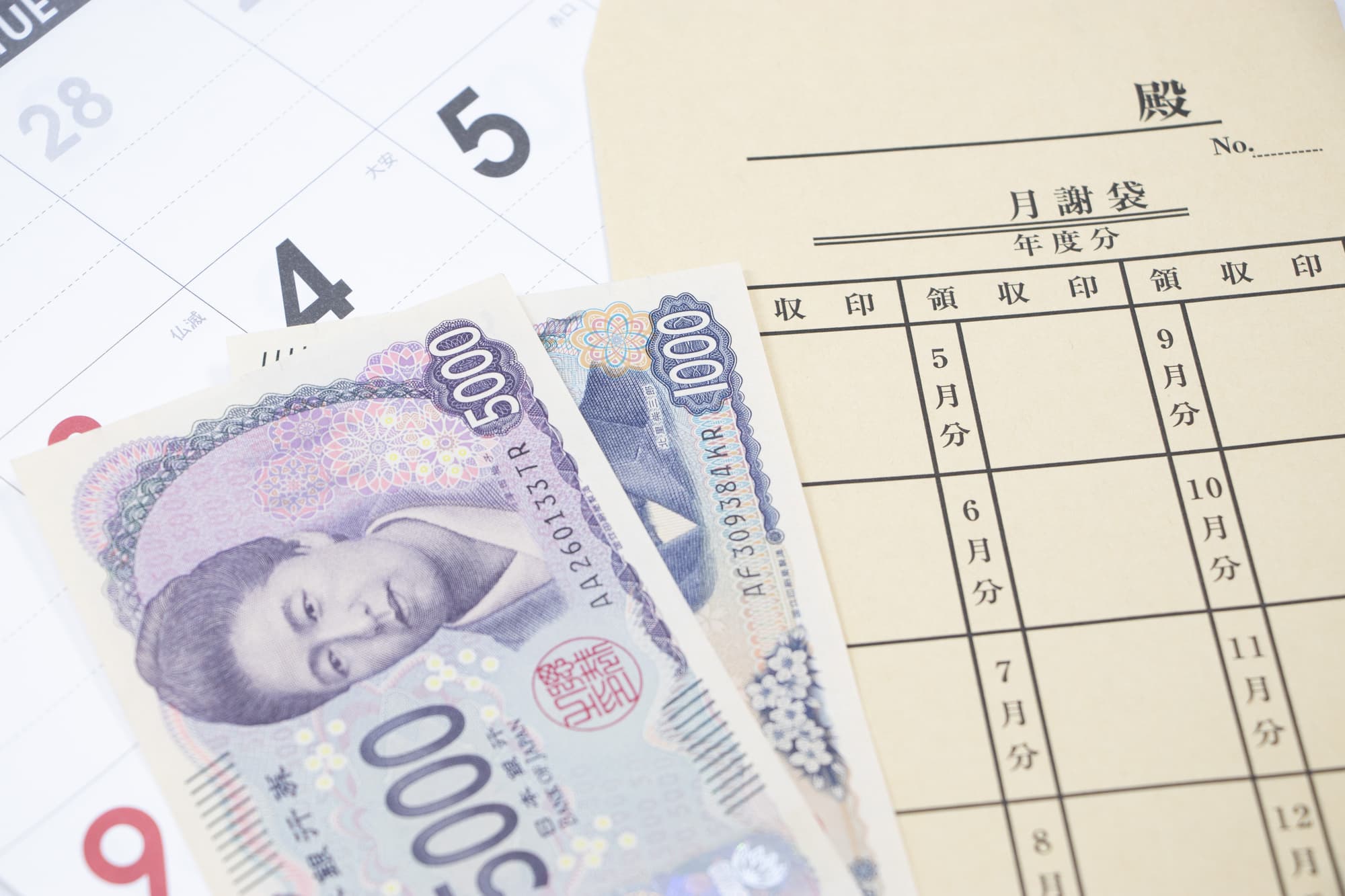 カレンダーの上に置かれた集金袋と紙幣