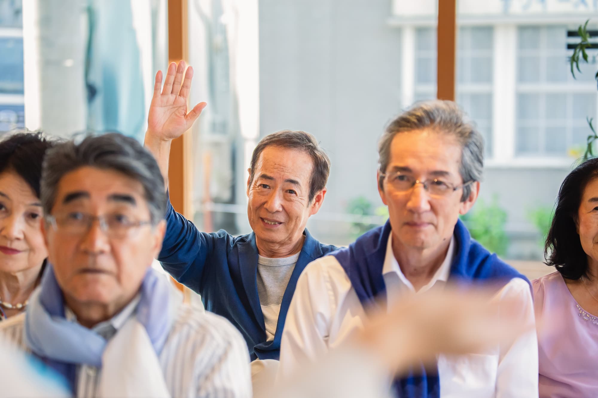 集まっている大勢の人の中で挙手している人