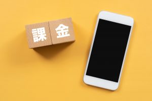 「課金」と書かれた木のブロックとスマホ