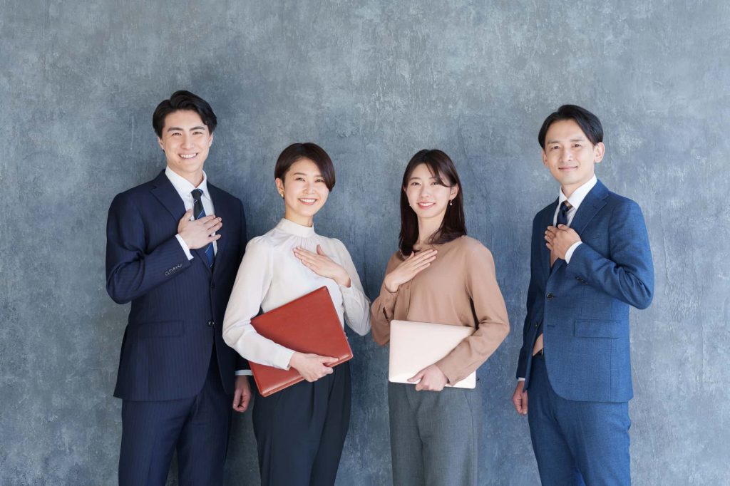 胸に手を当てて自信を示す4人のビジネスパーソン