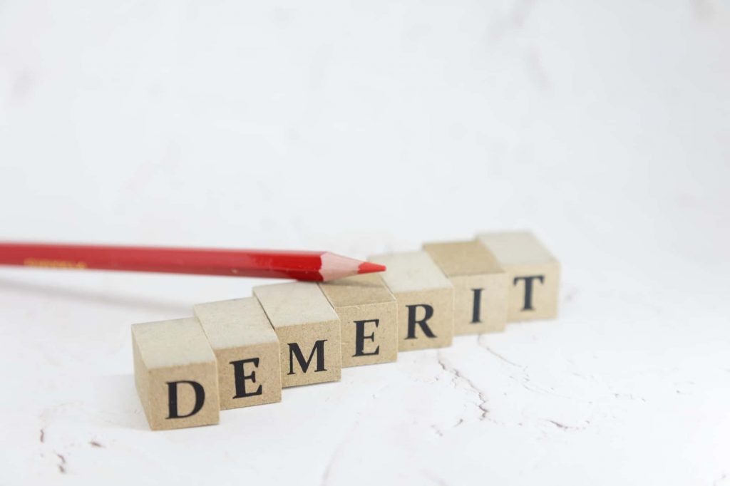 DEMERITと書かれているブロックと赤鉛筆