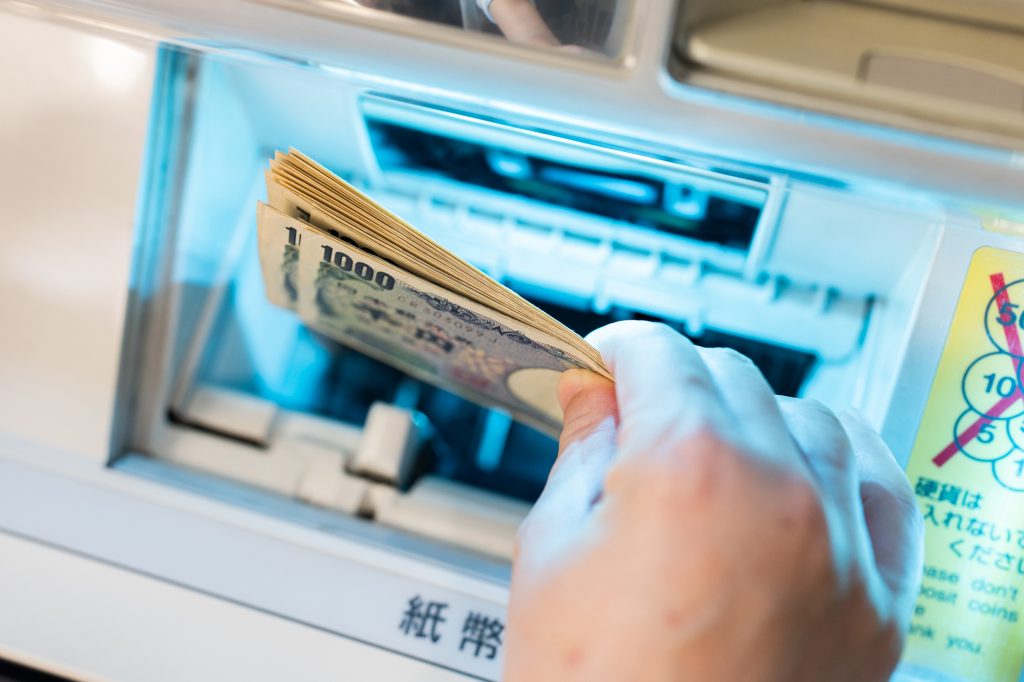 ATMに紙幣を入金している人の手元 
