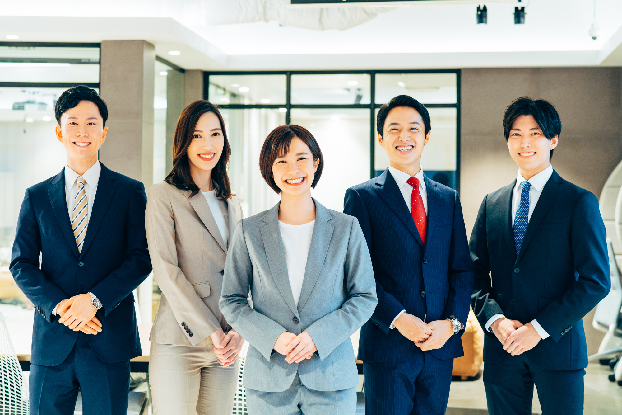 手を前に組むスーツの男女5人