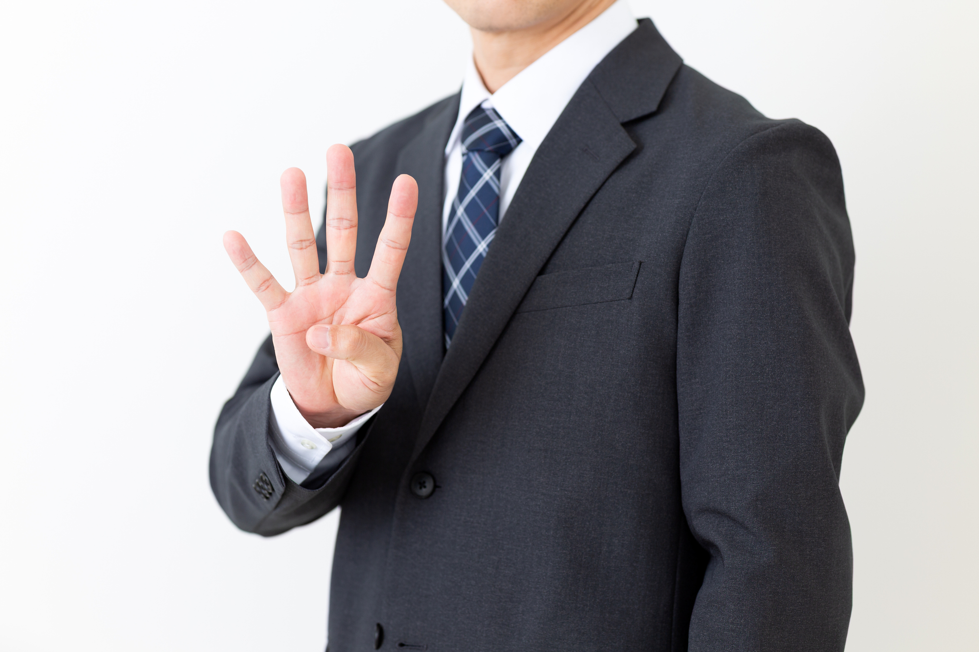 指で「4」を表すビジネスパーソン