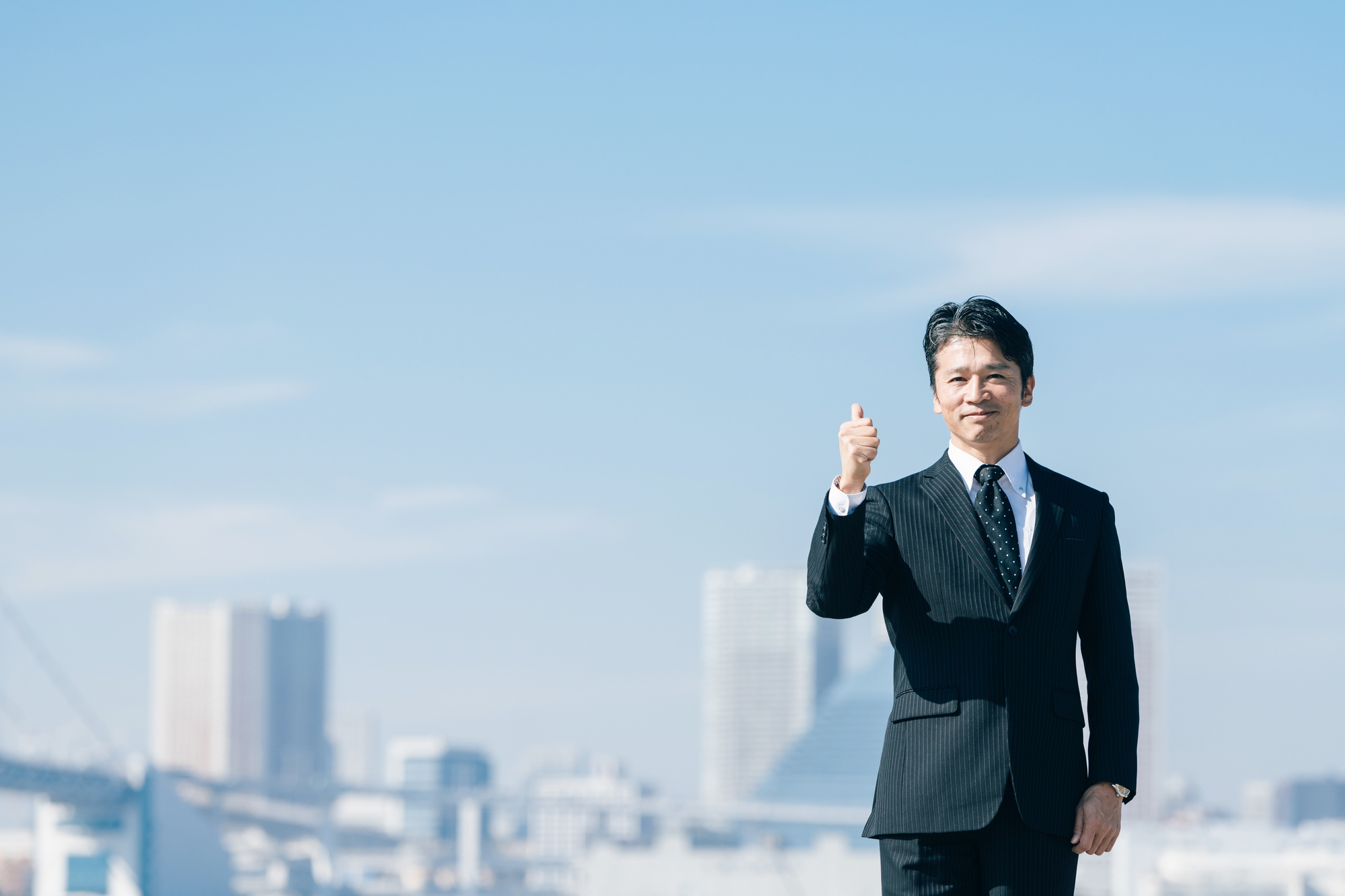 青空を背景に自信のある表情を浮かべるビジネスパーソン