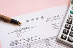 デスク上に置かれた請求書とボールペン、電卓