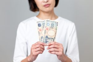 紙幣を手に持ち悩んだ様子の女性