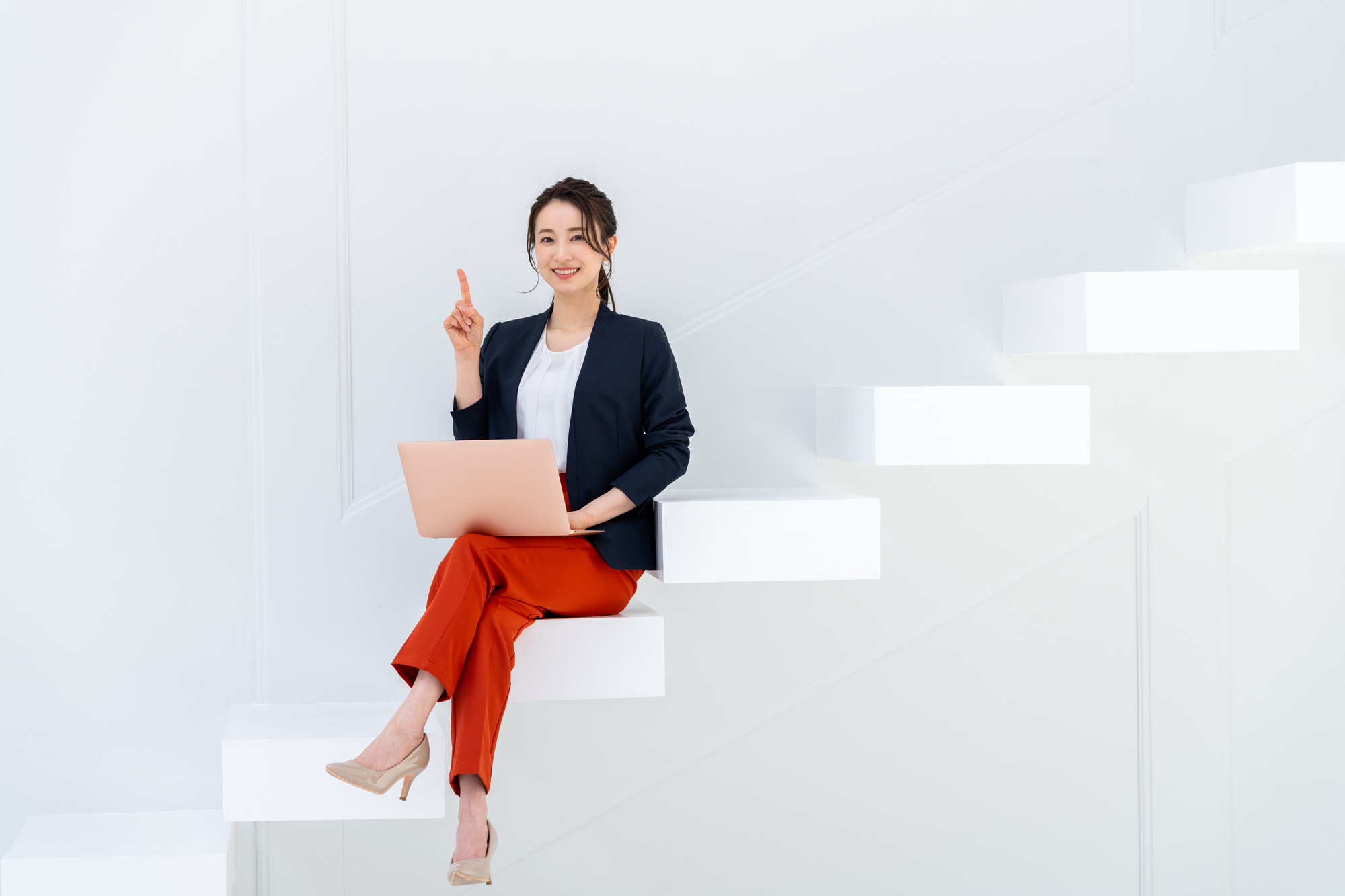 人さし指を立てて階段に座る笑顔の女性