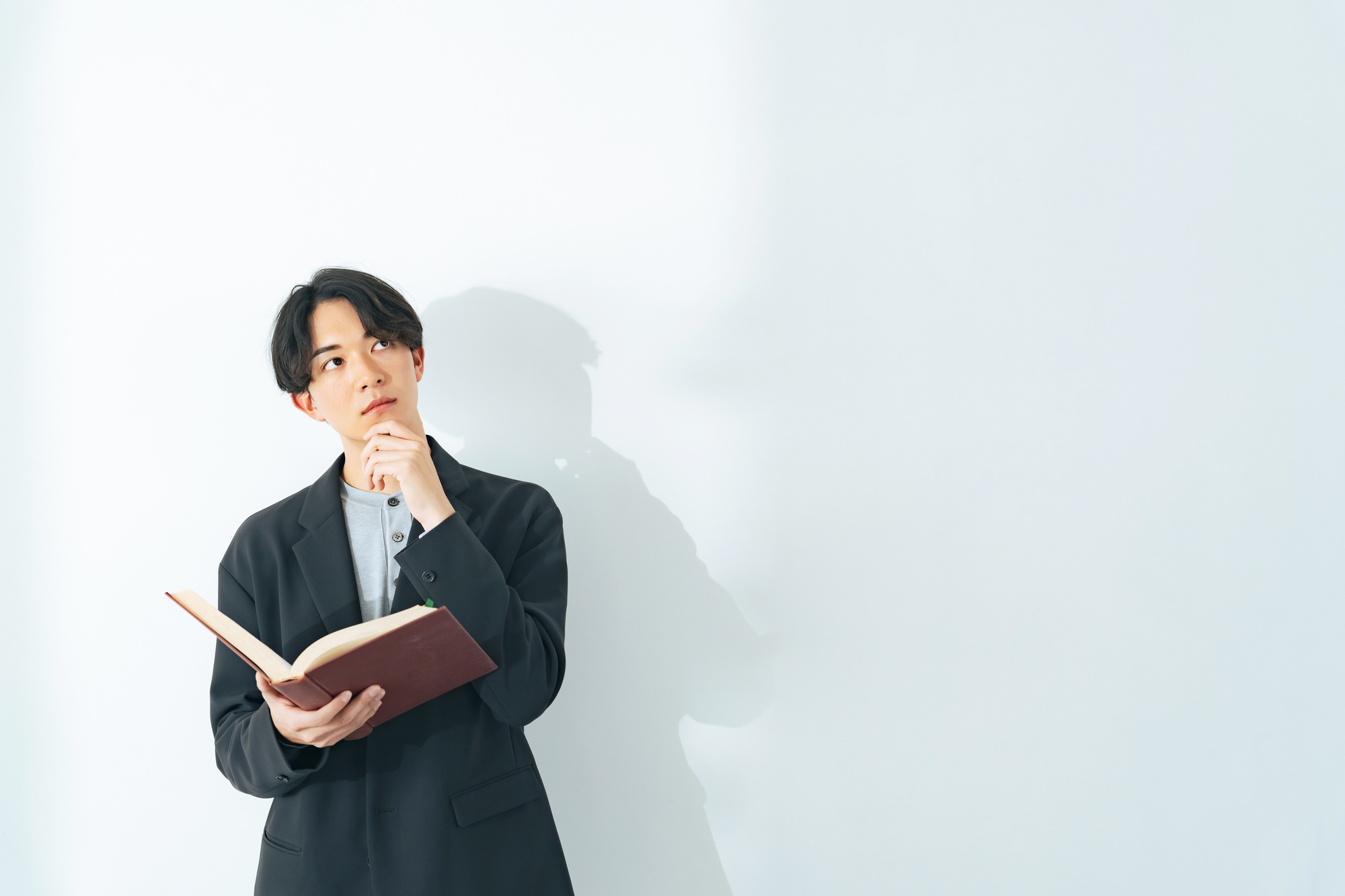 本を片手に首をかしげている男性