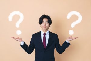 両手を広げたビジネスパーソンと２つのクエスチョンマーク