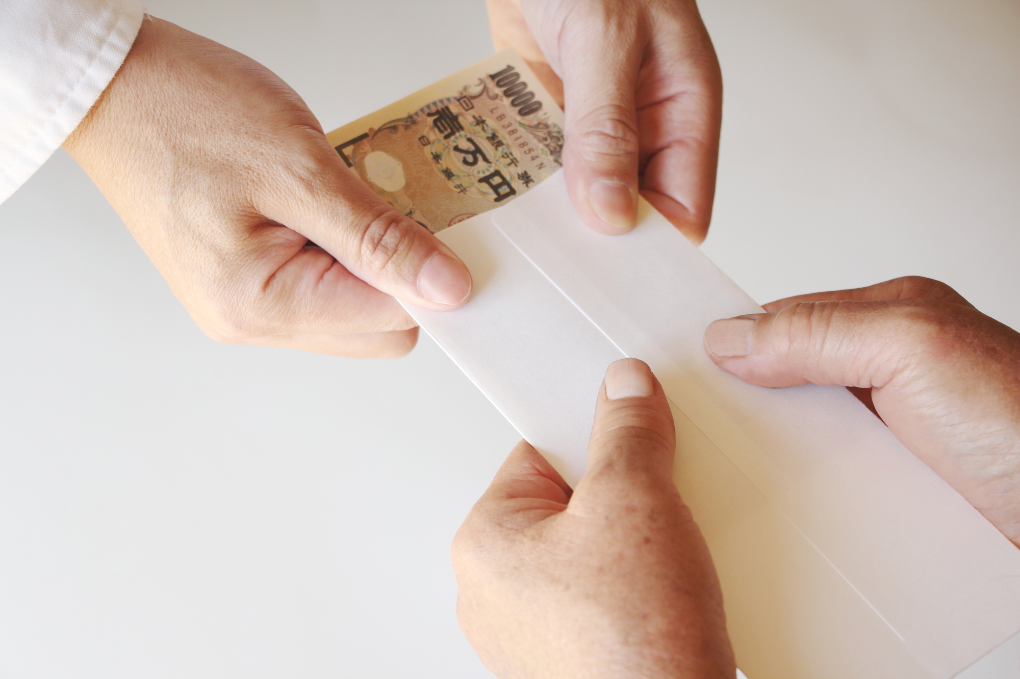 封筒に入った現金を手渡ししている様子