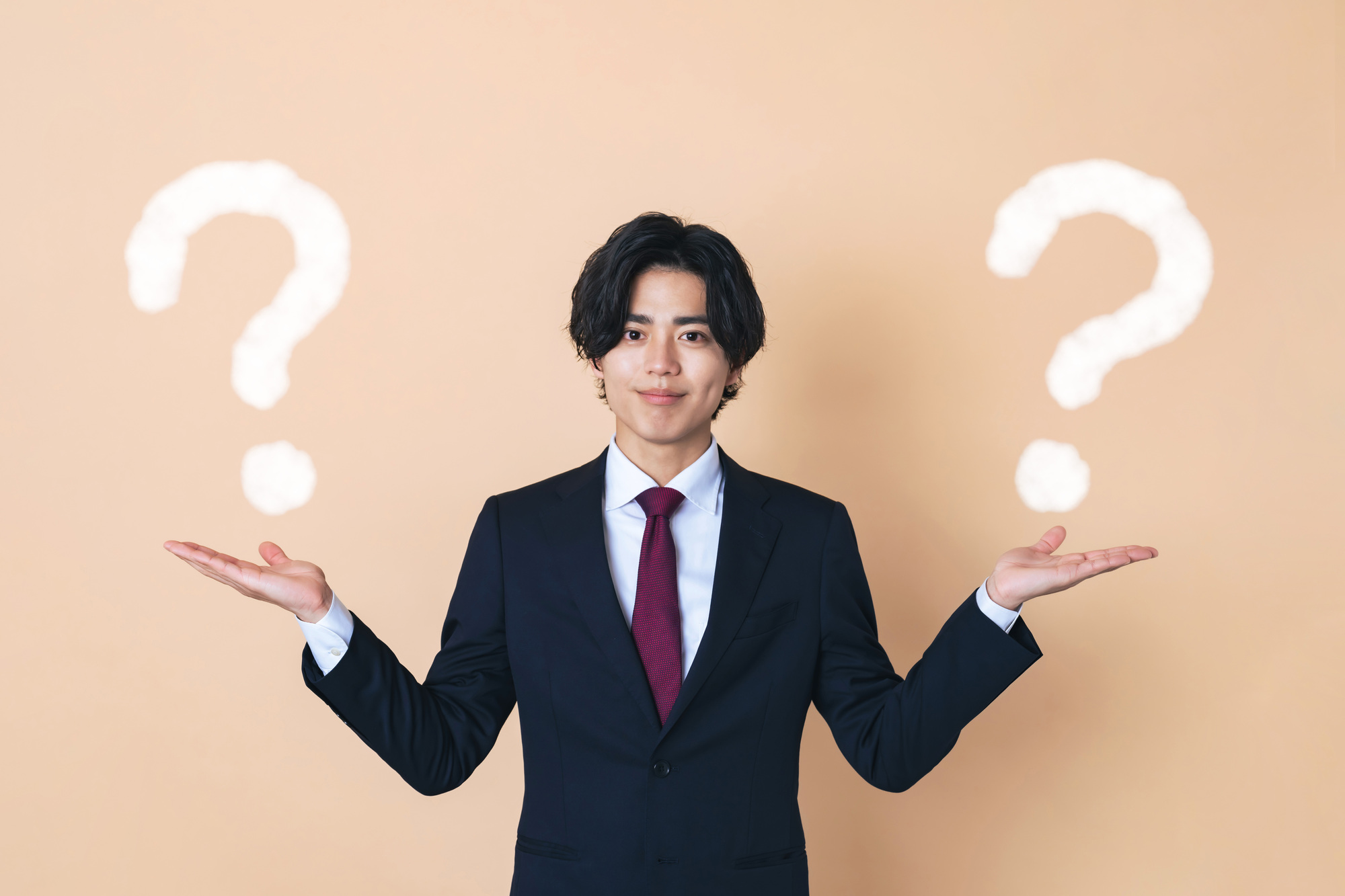 両手を広げたビジネスパーソンと２つのクエスチョンマーク