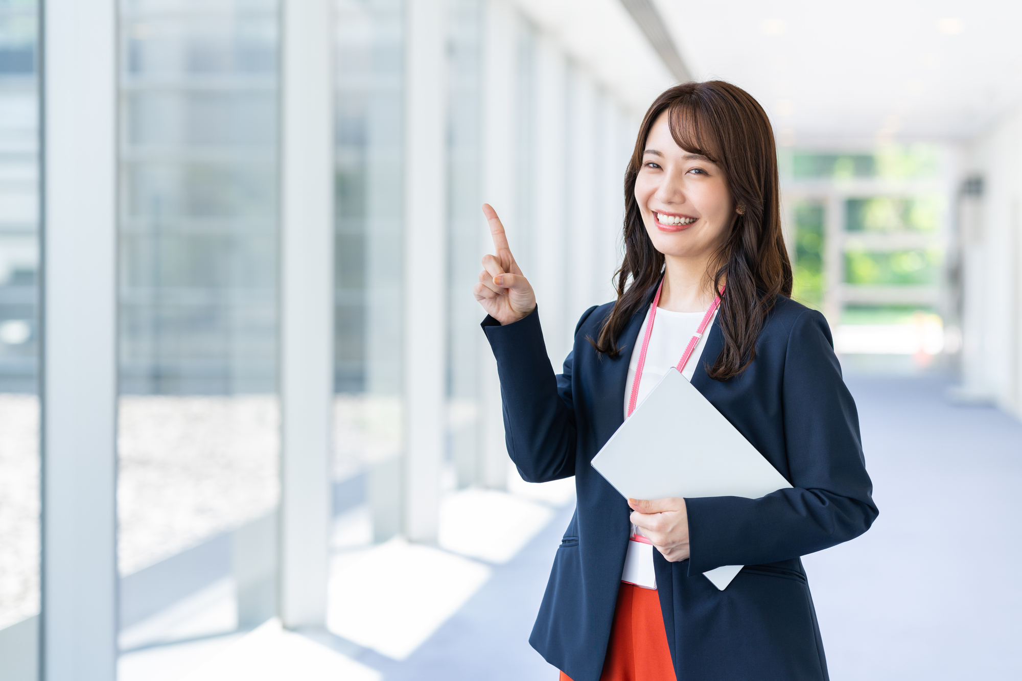 人さし指を上に向けた笑顔の女性