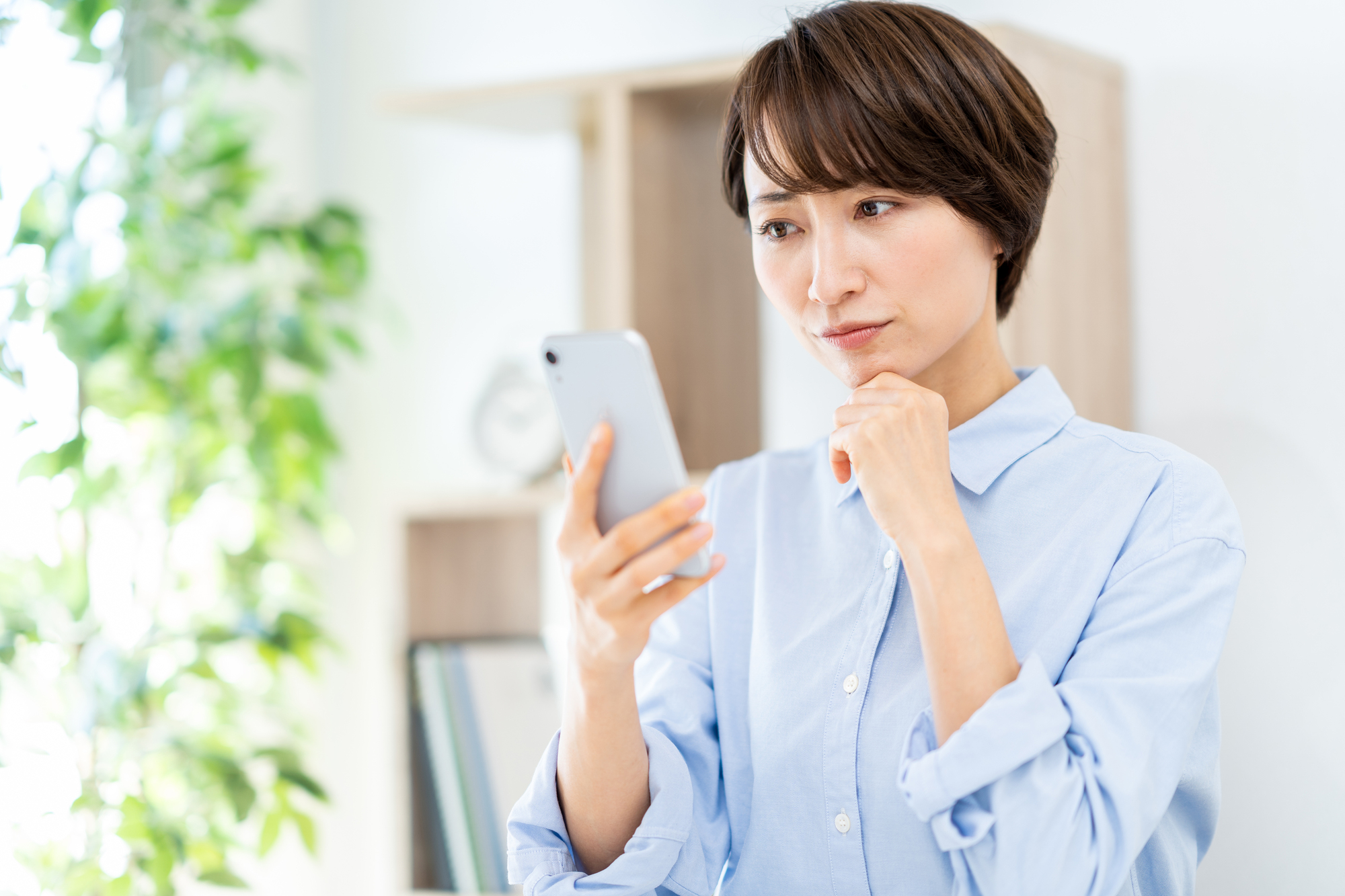 スマホを見ながら考えている様子の女性