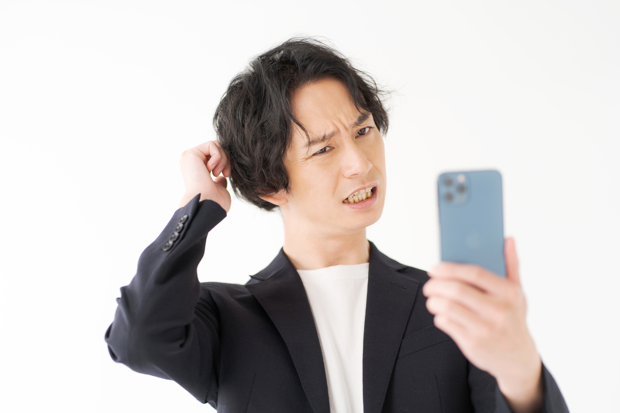 スマホを見ながら頭を抱える男性