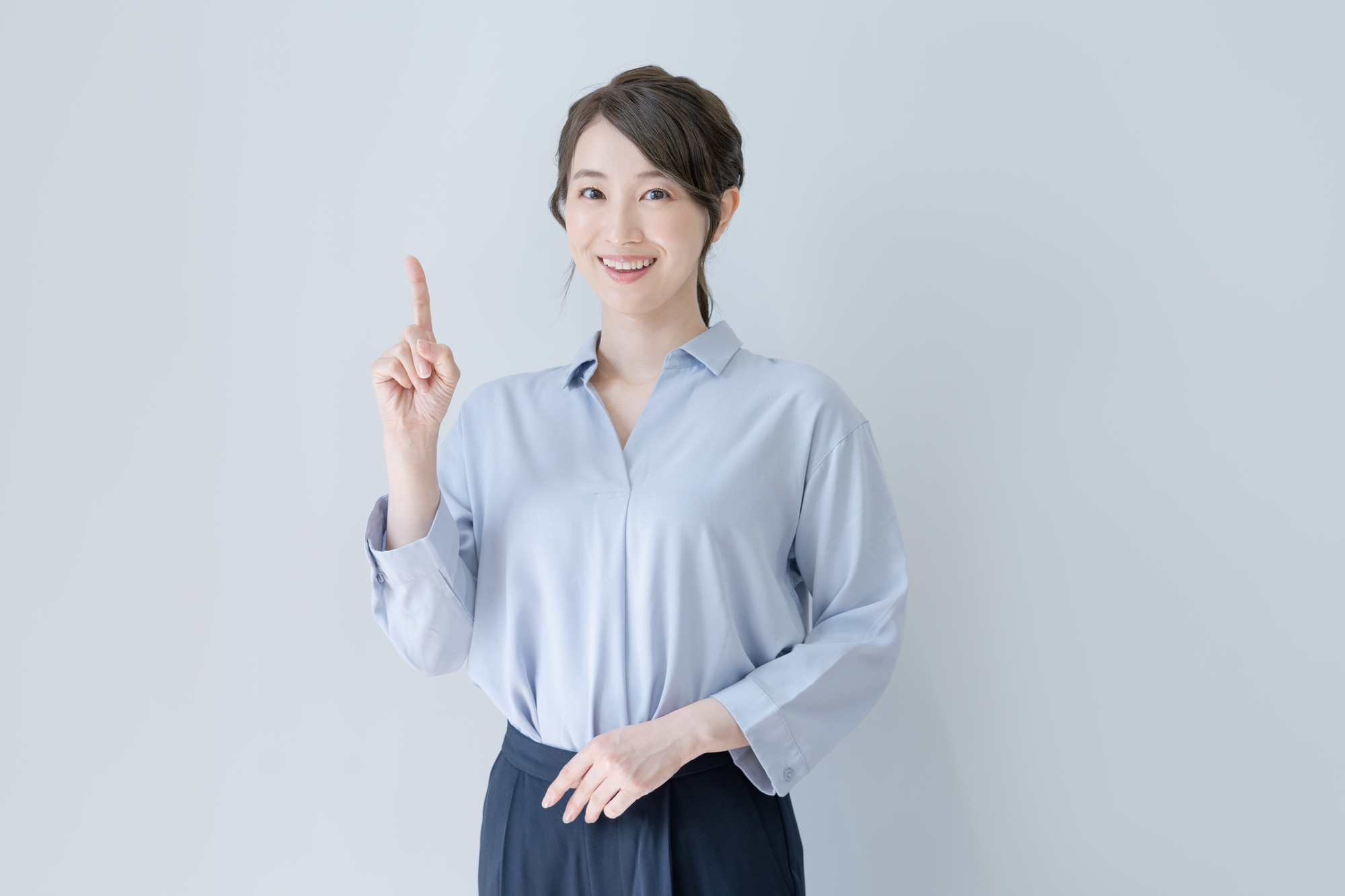 人さし指を立てて笑顔でこちらを見る女性