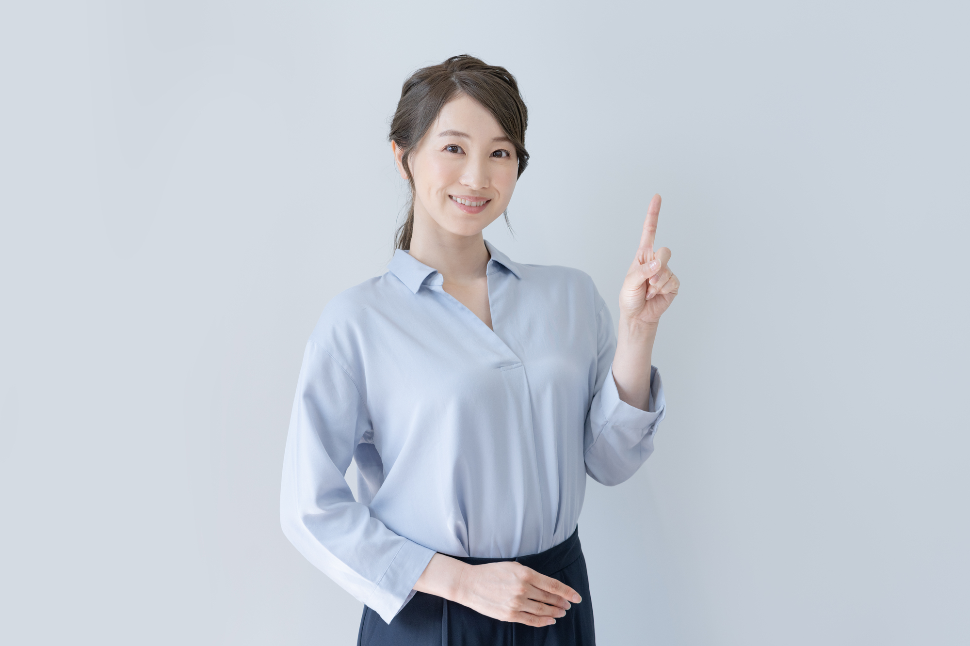人さし指を立てて笑顔でこちらを見る女性のポートレート