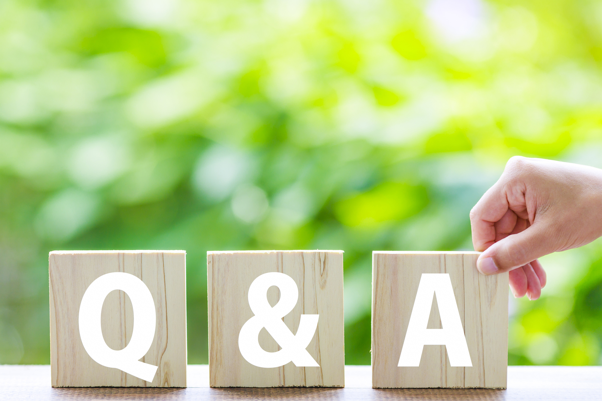Q&Aと書かれた木のブロック、Aのブロックの端をつかむ手