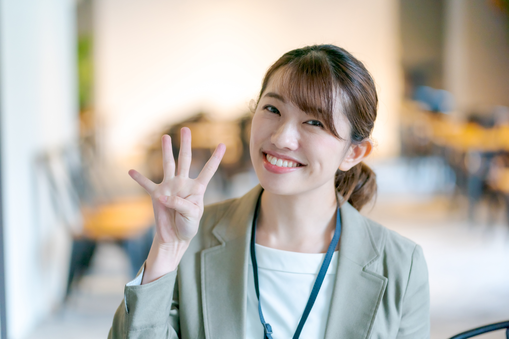 4本の指を立て笑顔を浮かべる女性