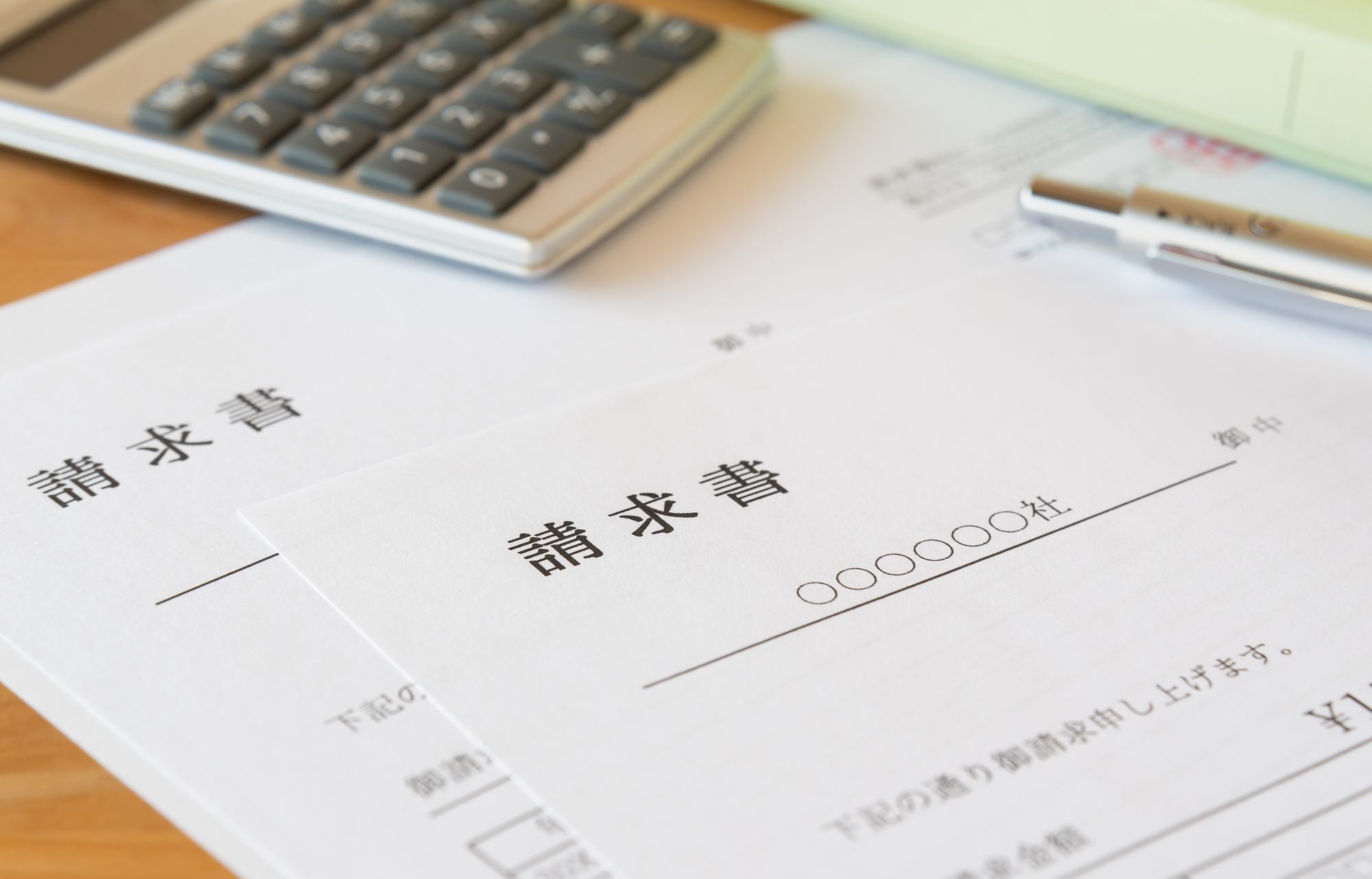 机の上に置かれた2枚の請求書と電卓