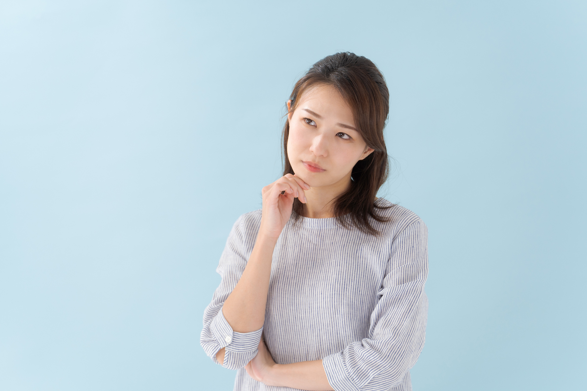 右手を顎に当て、首を傾げる女性のポートレート