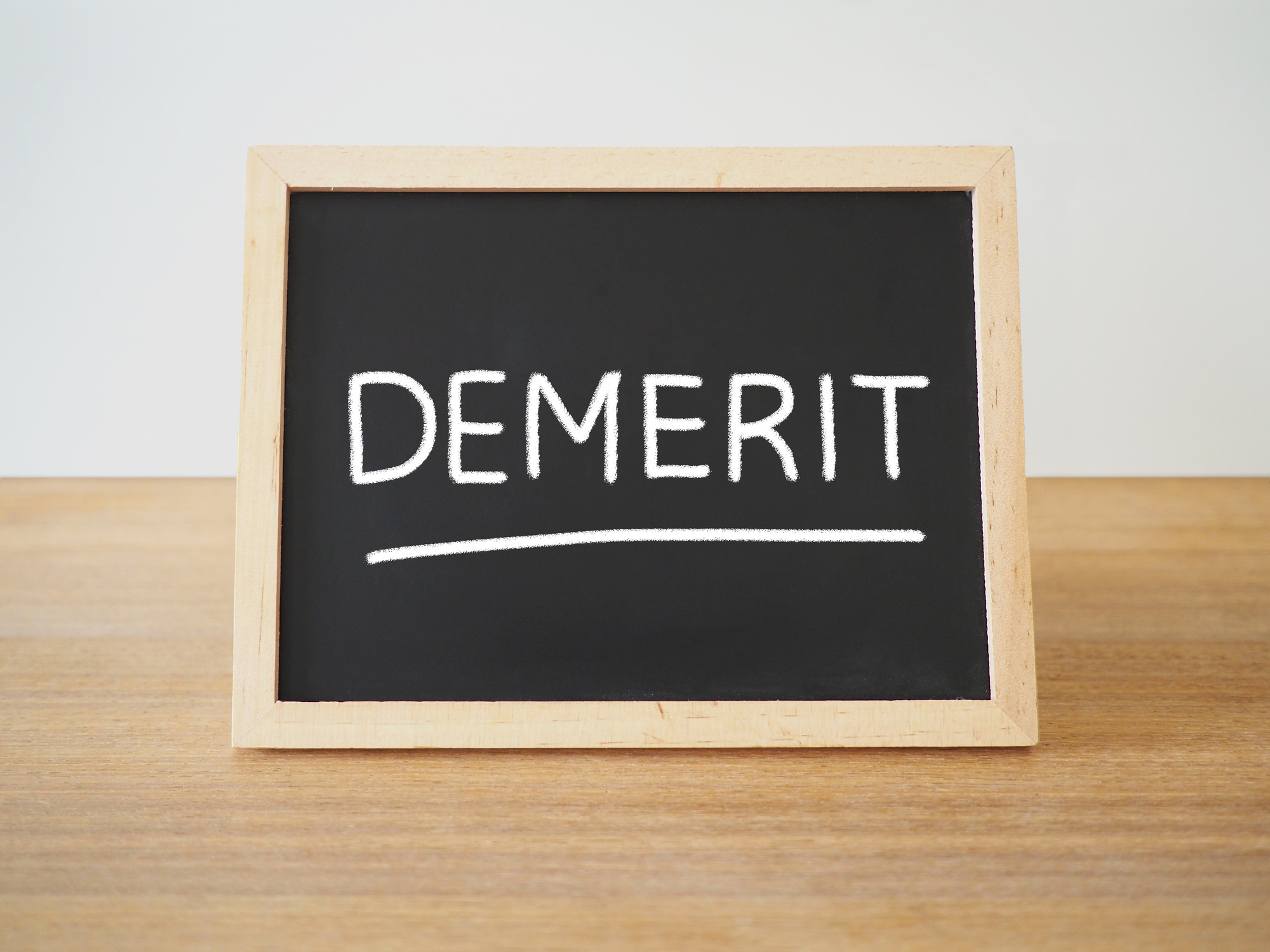 木製のデスク上に置いてあるDEMERITと書かれたボード