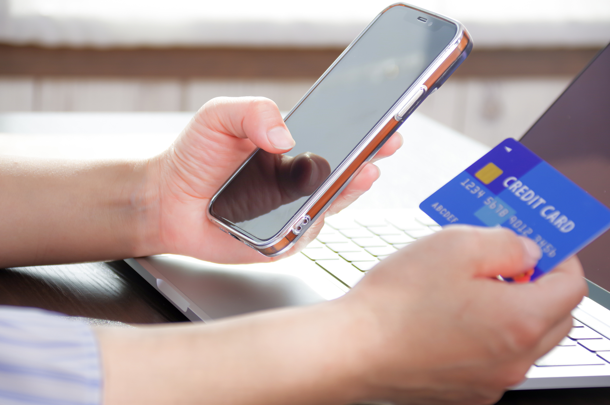 クレジットカードとスマホを持っている人の手元