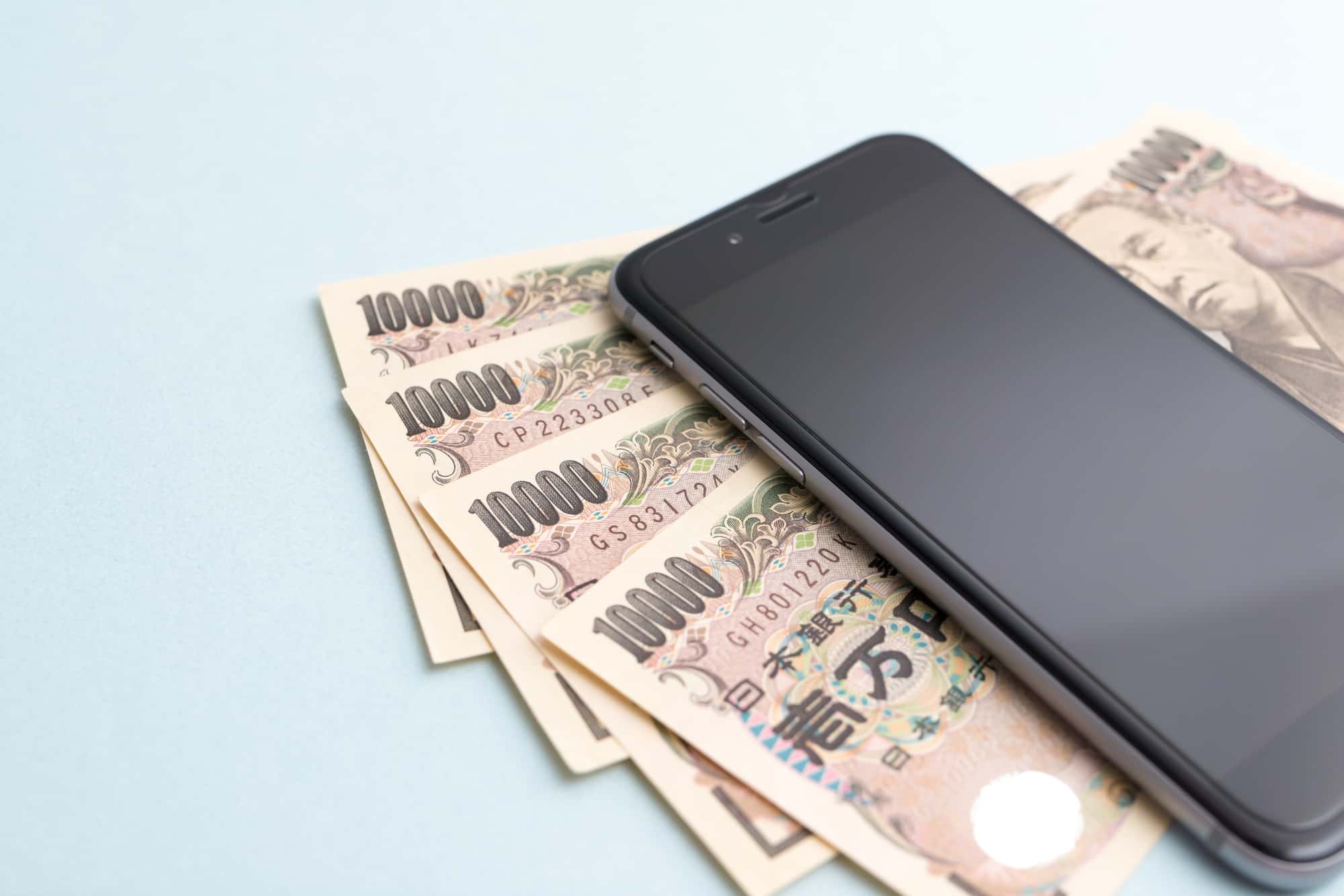 4枚の紙幣とスマートフォン