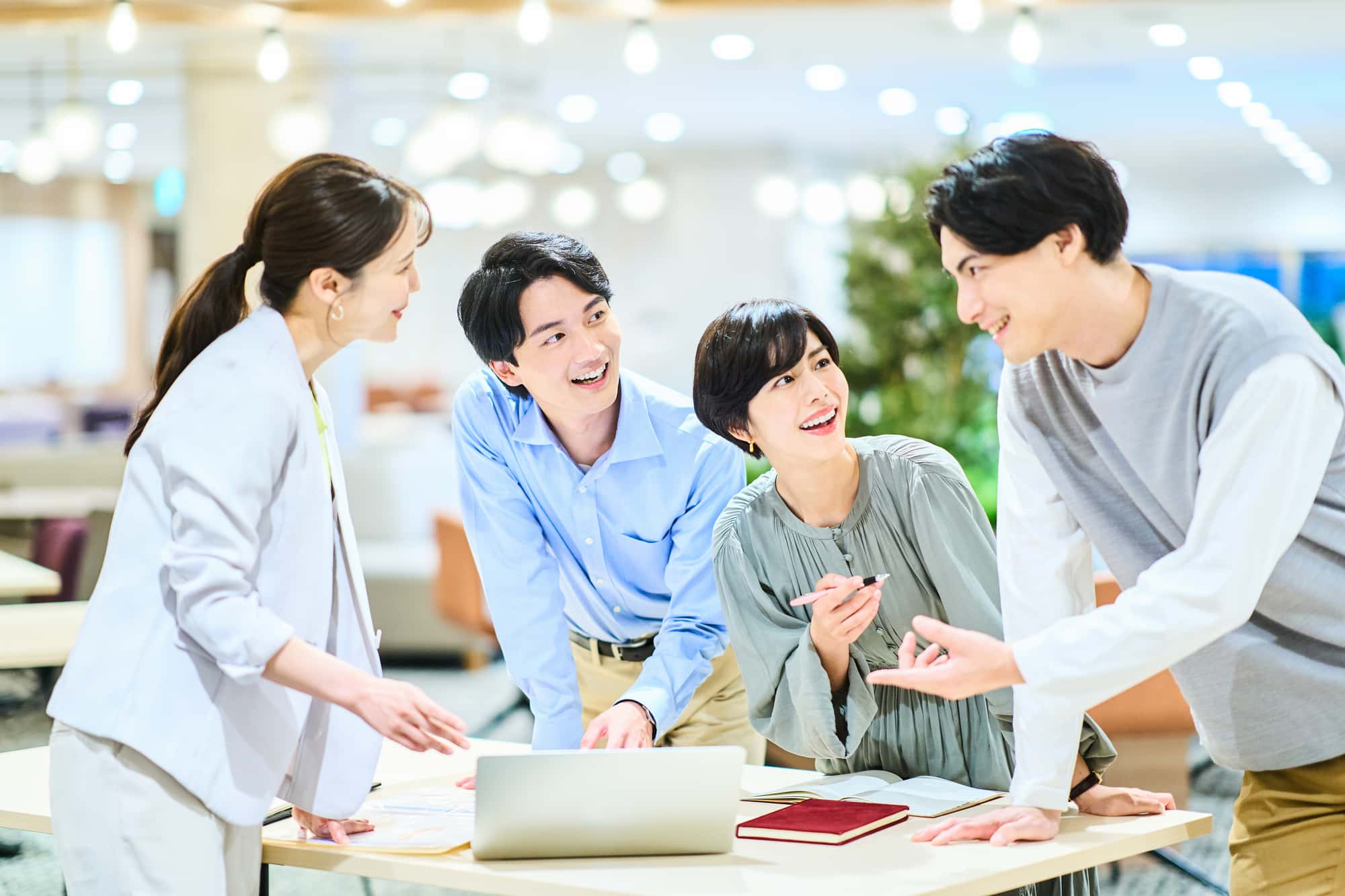 オフィスで和やかに会議を行っている4人のビジネスパーソン