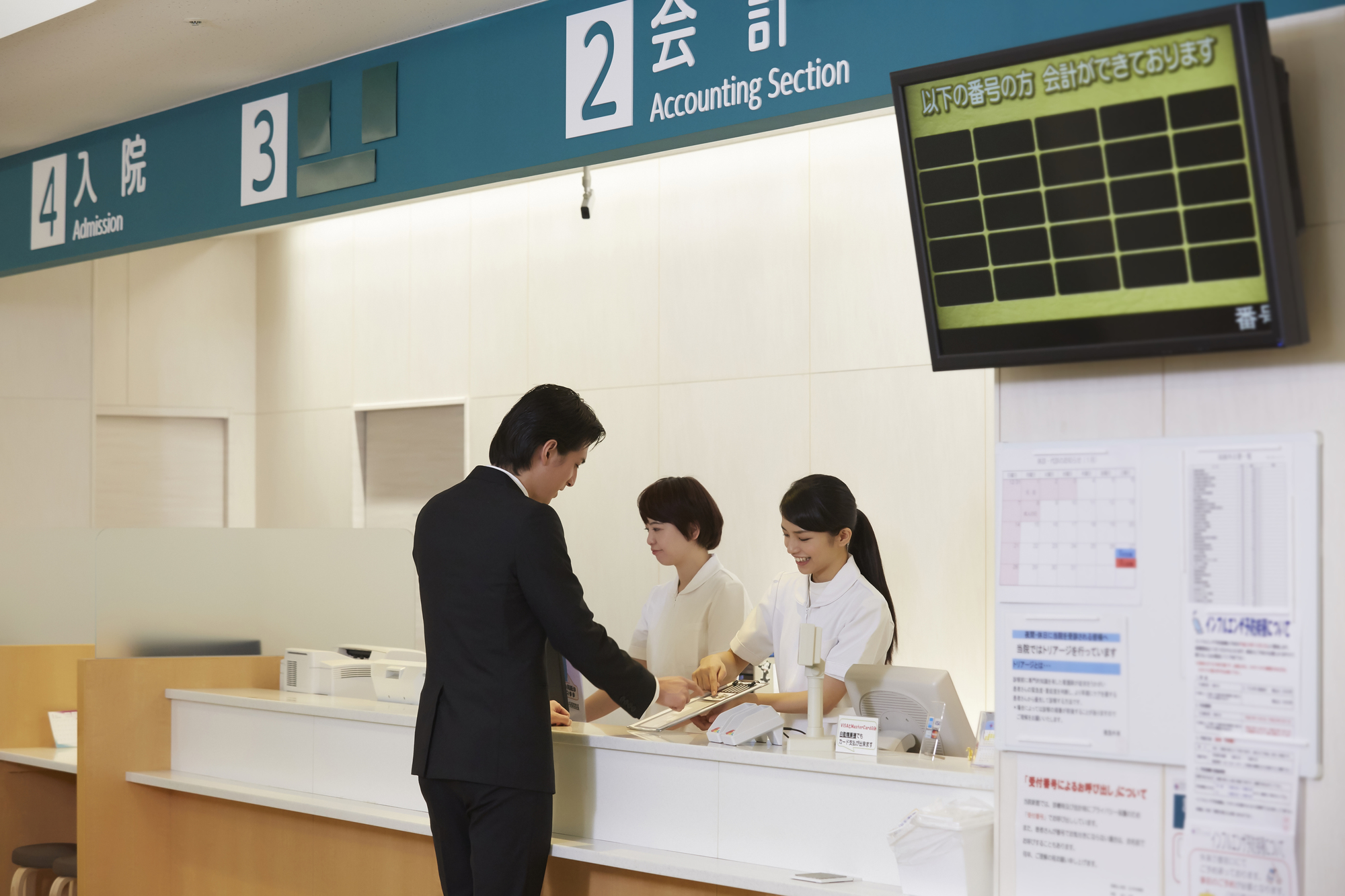 病院のカウンターで会計しているスタッフと患者