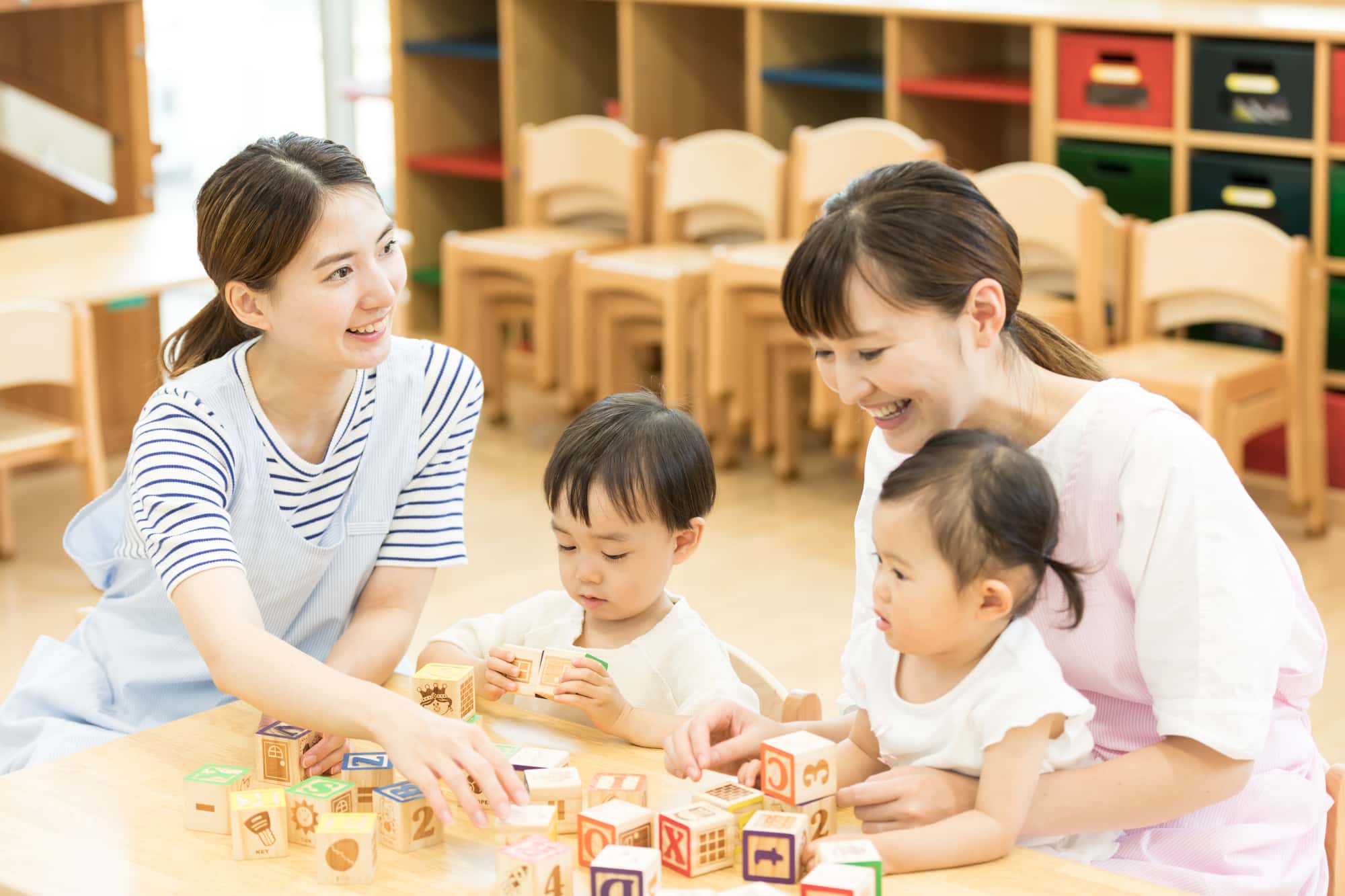 保育園内で遊んでいる子どもと保育士