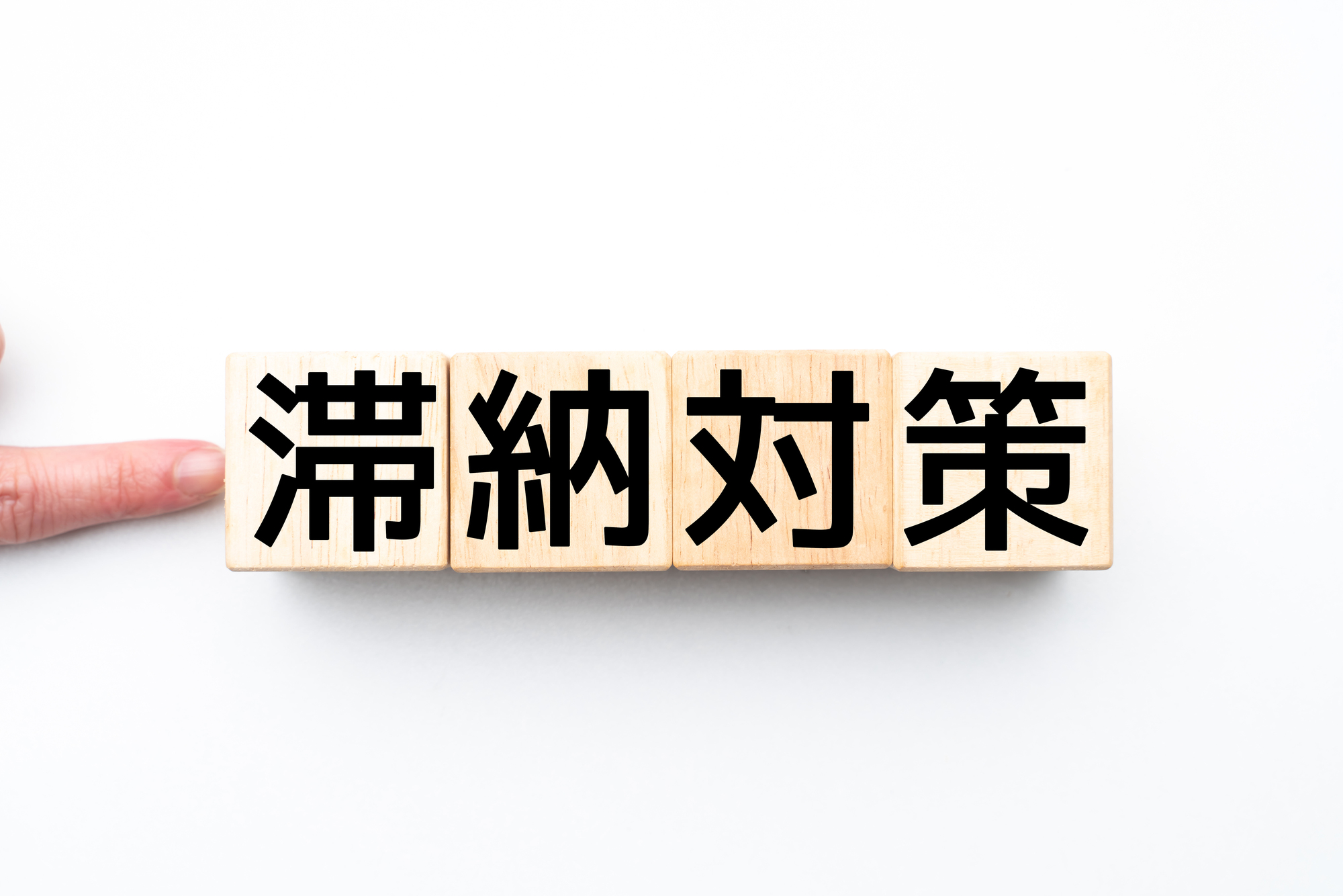 滞納対策と書かれたブロックを指さしている人