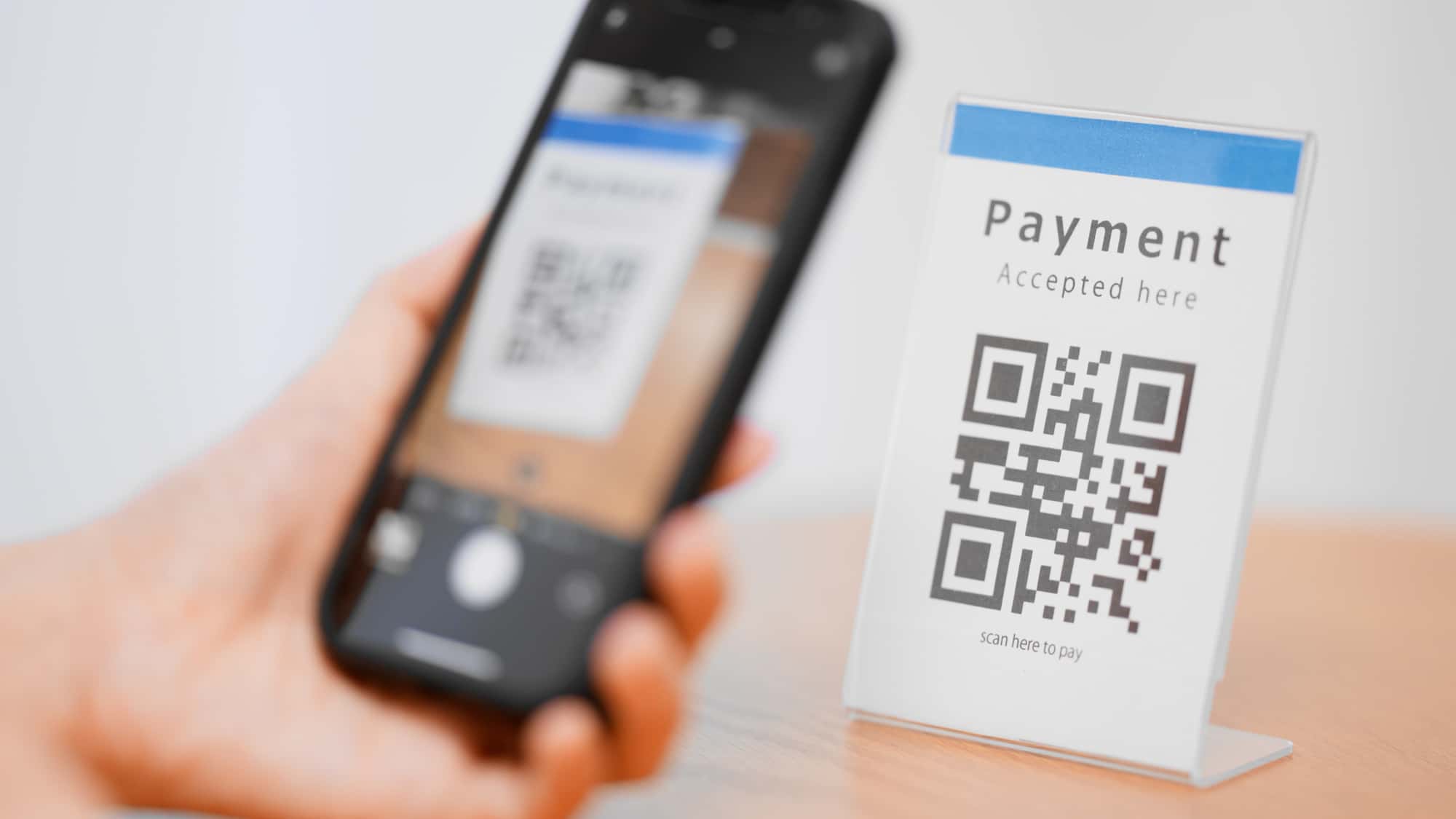 決済用の二次元コードをスマホでスキャンしている人