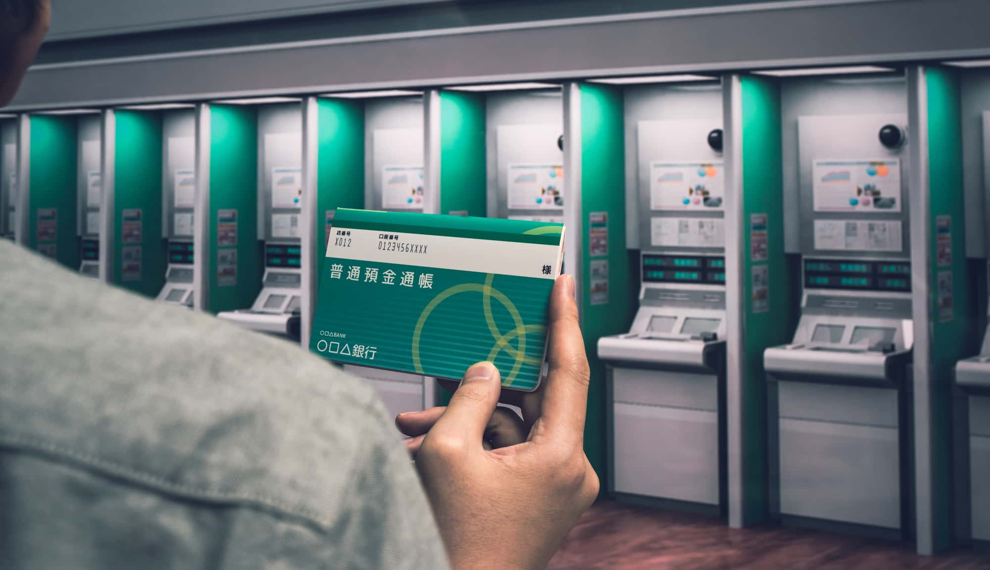 ATMの前で通帳を手にしている人