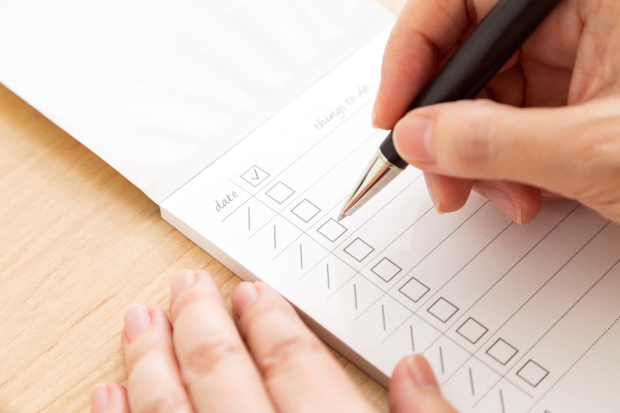 チェックリストにボールペンでチェックを入れている人