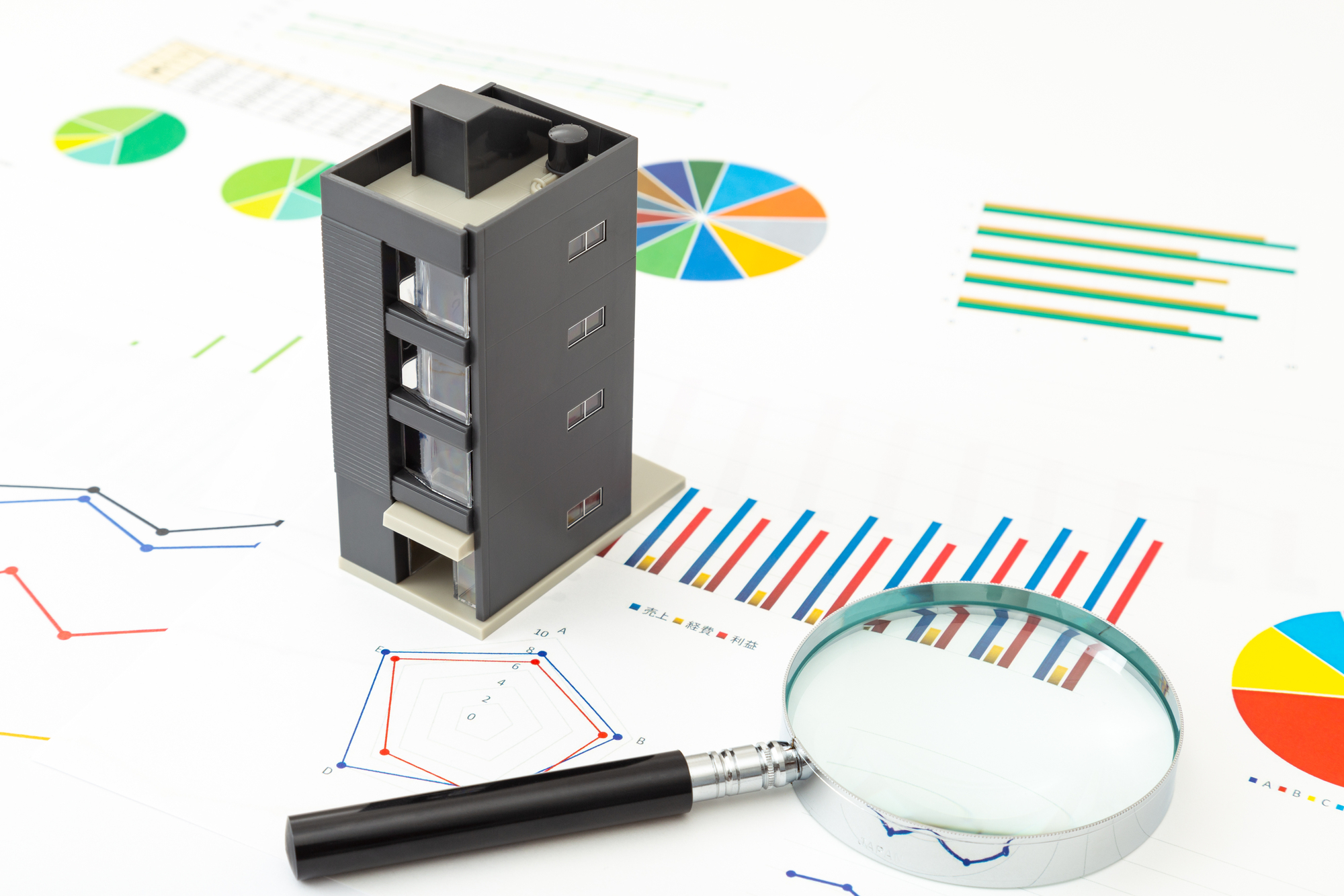 マンションの模型と虫眼鏡、印刷されたグラフ