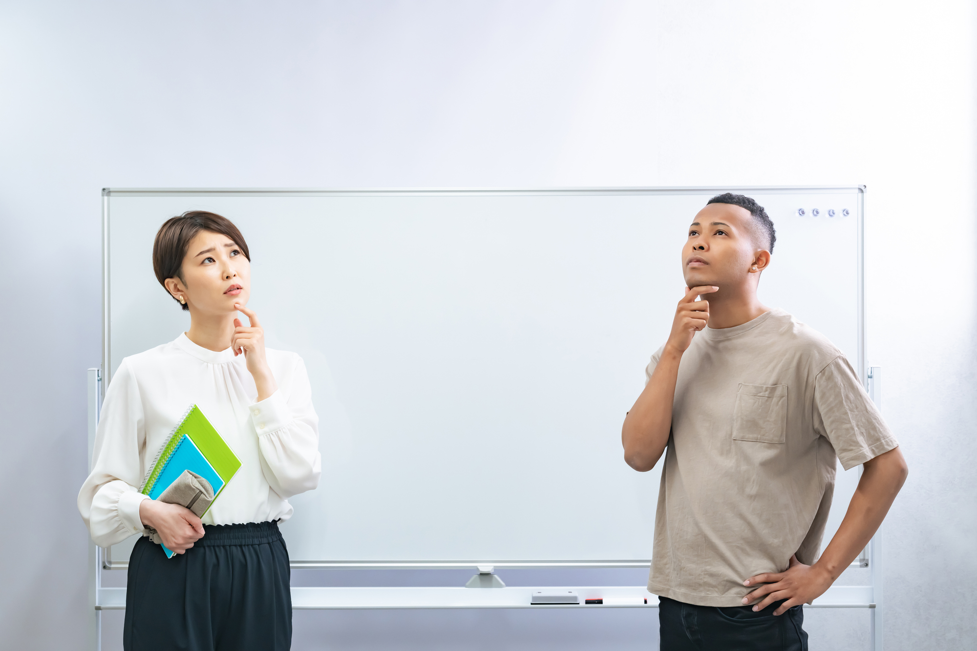 ホワイトボードの前で悩む2人の講師