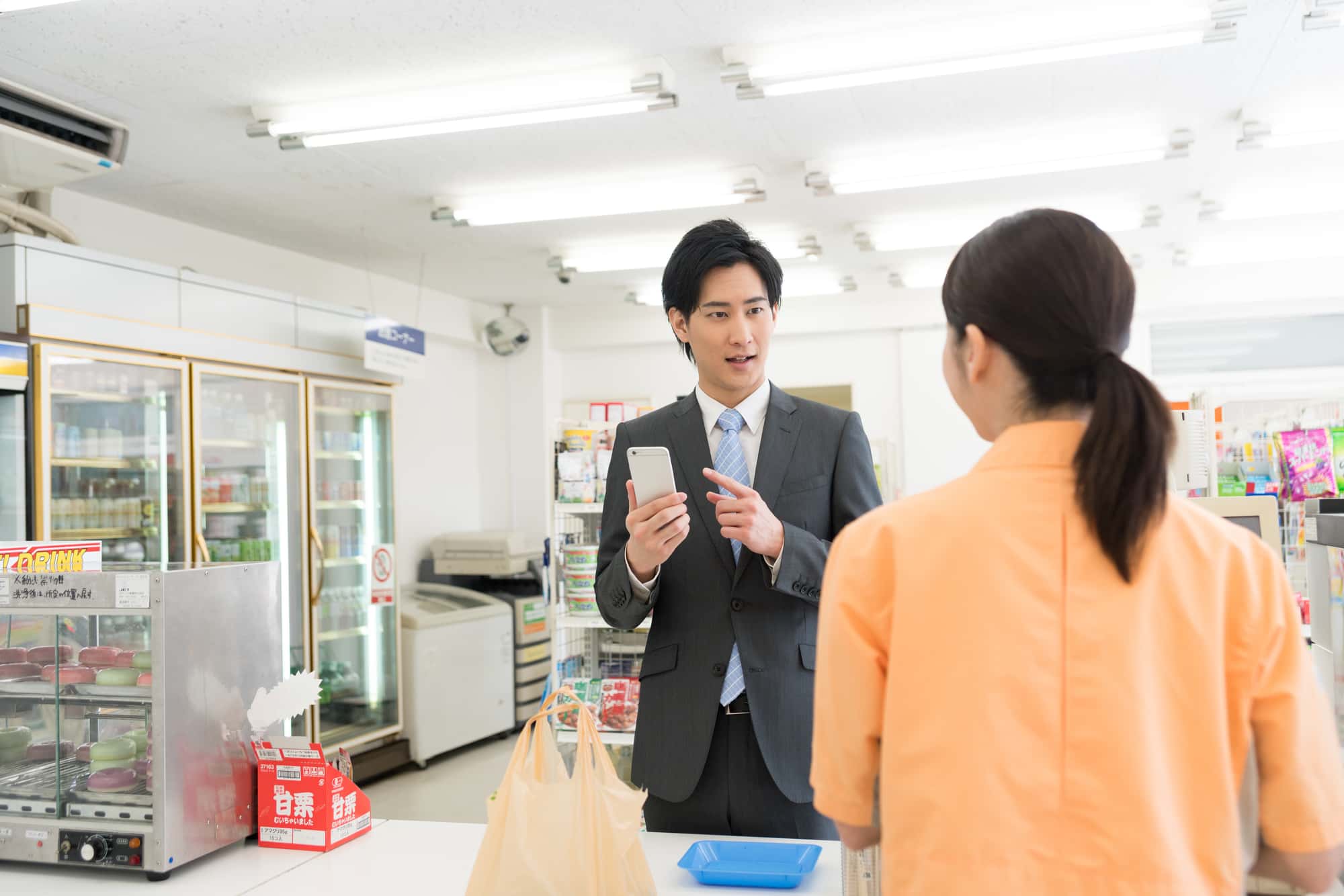コンビニのレジにいる利用者と店員