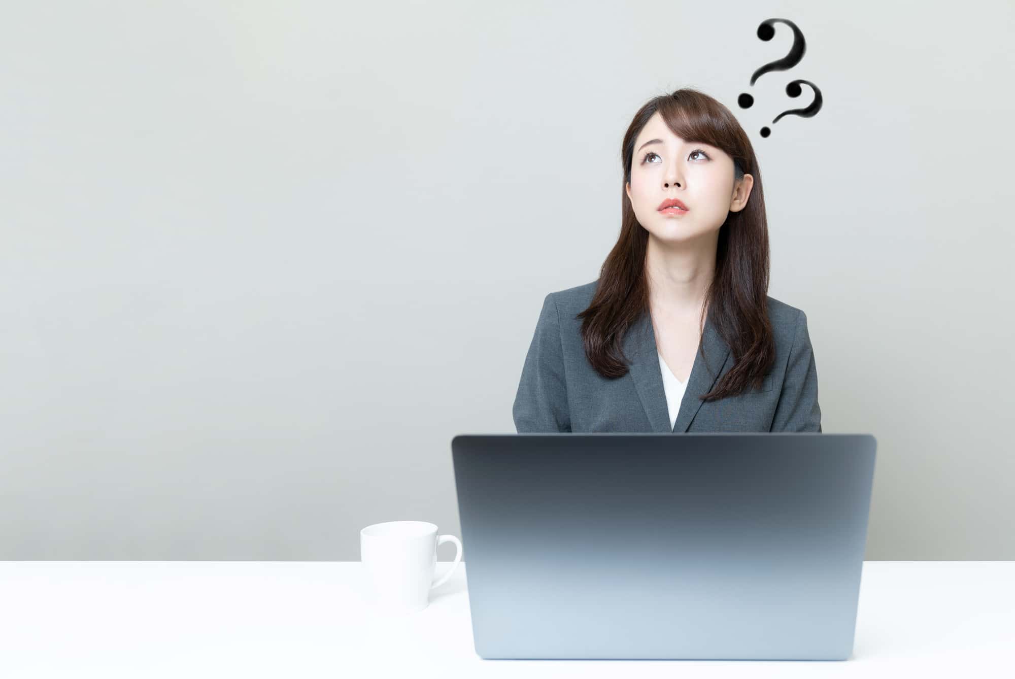 パソコンの前でクエスチョンマークを浮かべる女性