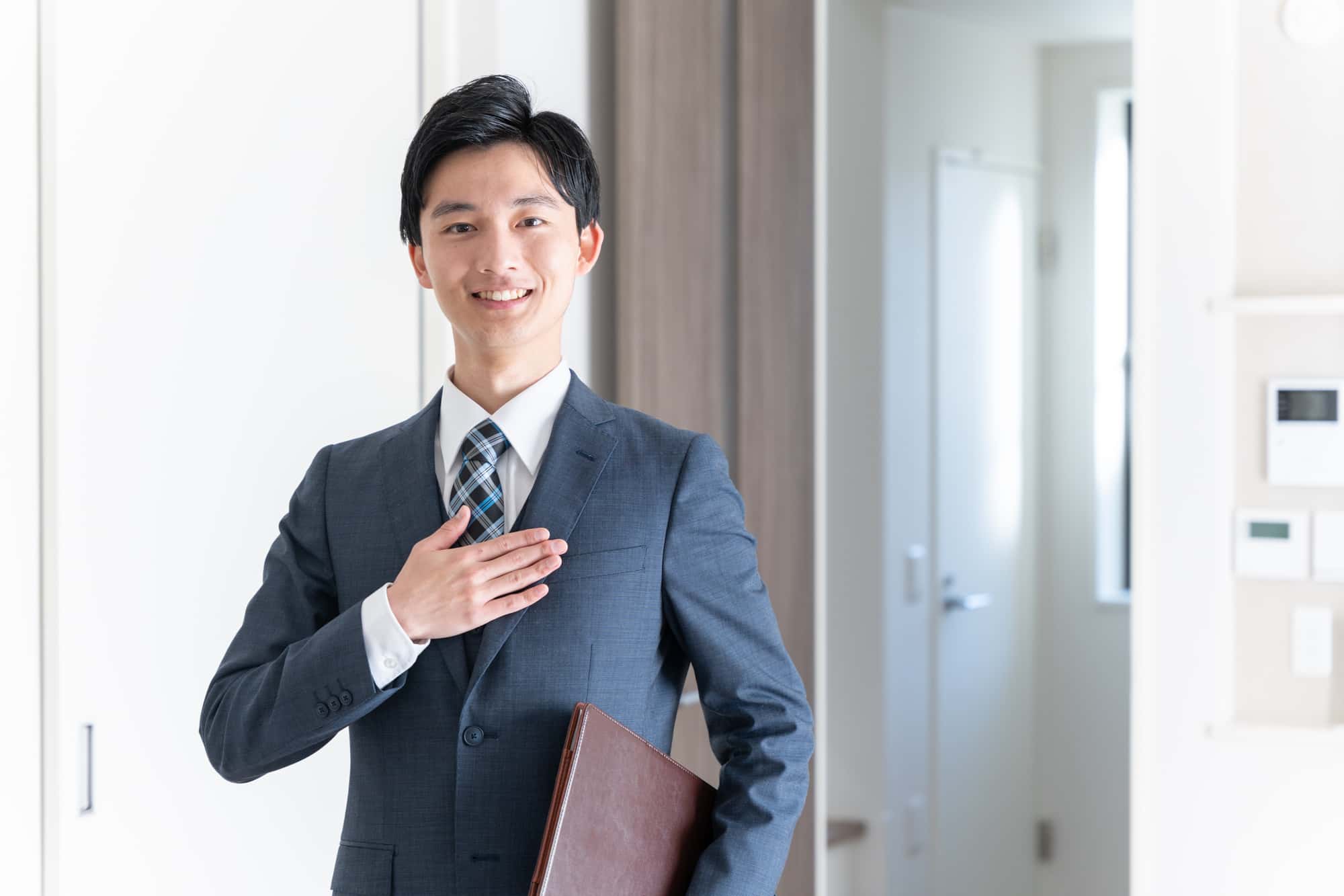 胸に手を当てて笑顔を浮かべるビジネスパーソン