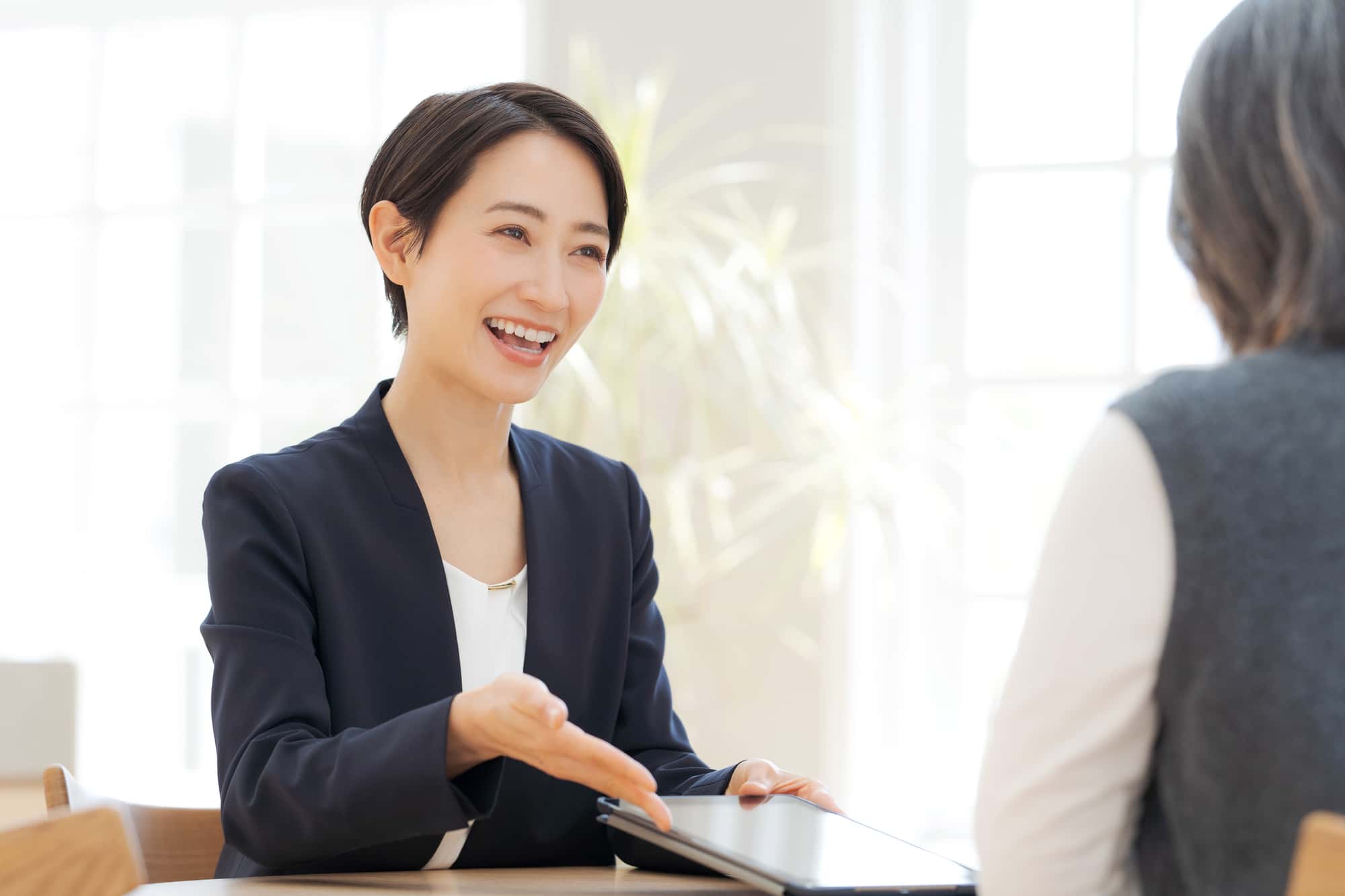 タブレットの画面を見せながら笑顔で説明を行っている女性